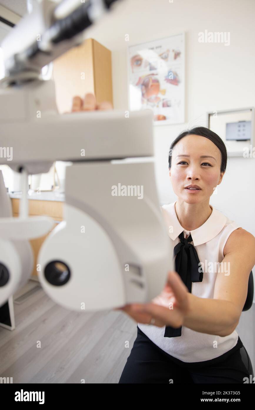 Female optometrist preparing phoropter in exam room Stock Photo Alamy