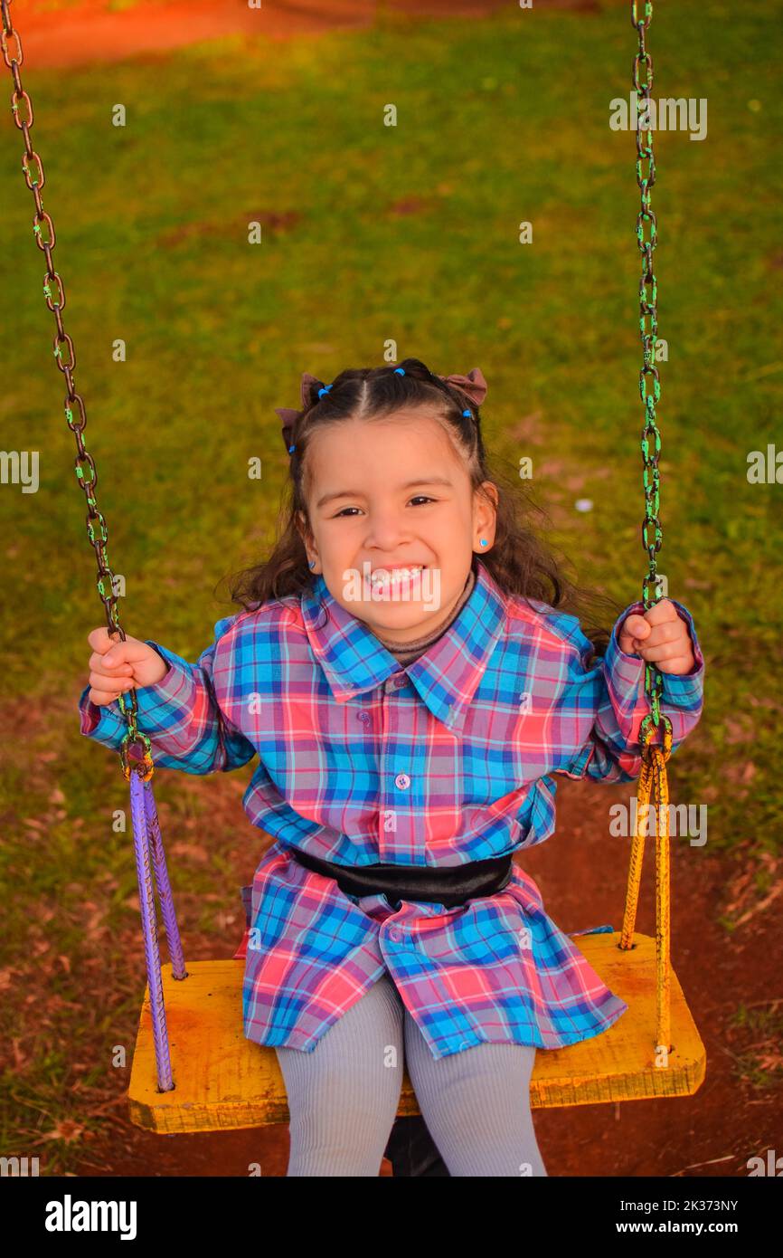 A vertical shot of a cute little girl in a plain blue pink dress on a ...