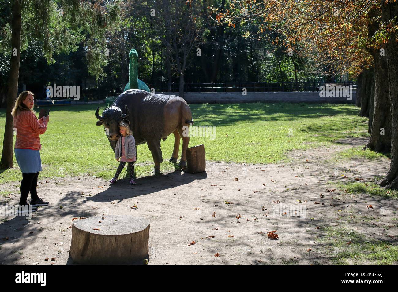 Mother is seen photographing her daughter near the bison figure. One of the oldest in Ukraine, the Odessa Zoo was established in September 1922 In honor of the centenary of the zoo, solemn events were held:1.? memorial plaque was opened to its first director Heinrich Beizert. 2.Ukrposhta issued a special envelope and a stamp. The circulation is limited, only 200 pieces. Stamp cancellation was carried out right at the zoo. 3.Together with the Odessa mayor Gennady Trukhanov, the director of the zoo, Igor Belyakov, opened a new lion cub.In April, a pair of white lions from the Feldman Ecopark in Stock Photo