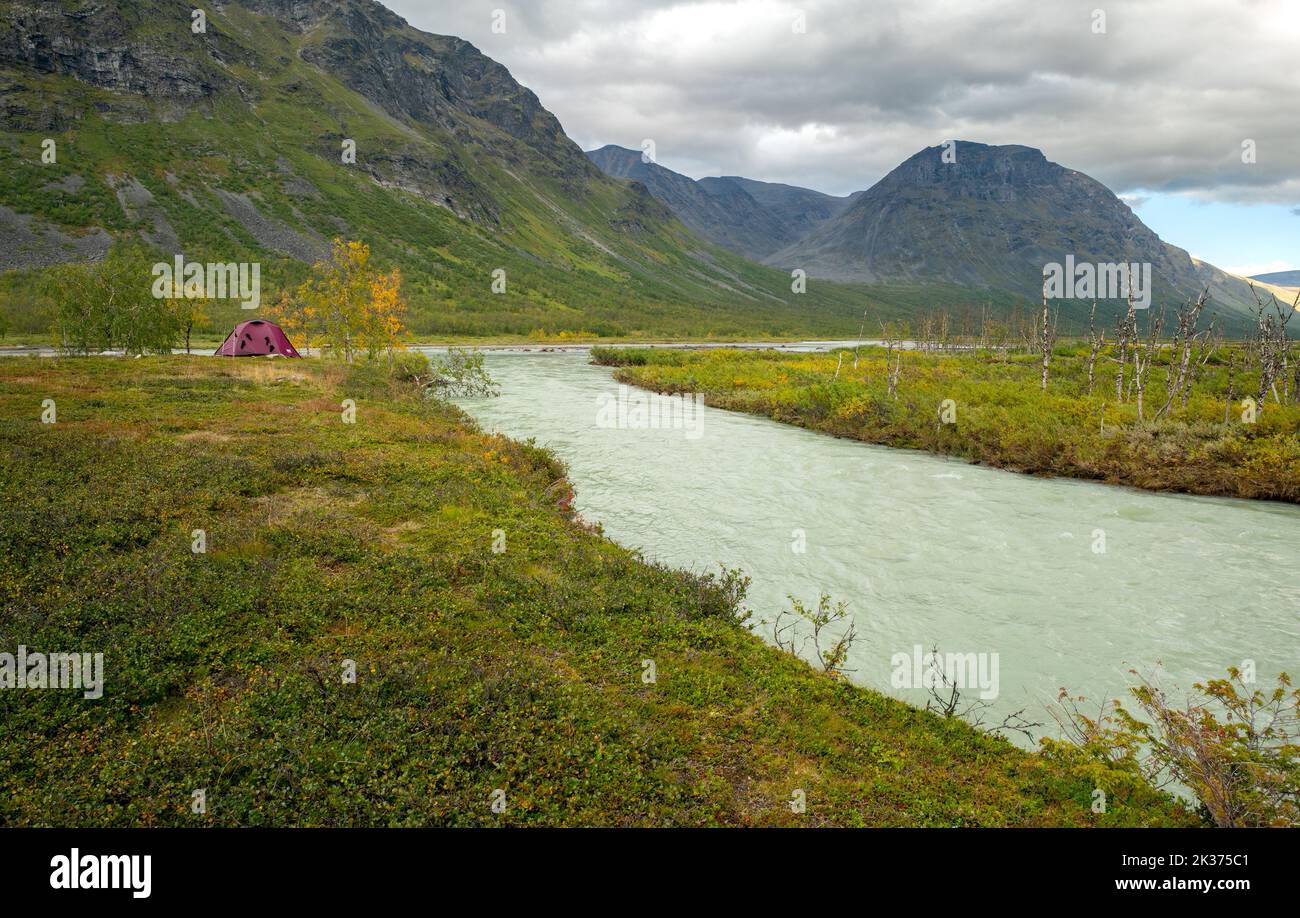 Outdoor tent in the remote Arctic valley under tall mountains of Sarek National Park, Lapland, Sweden. Rapadalen valley in the far north, Laponia Stock Photo