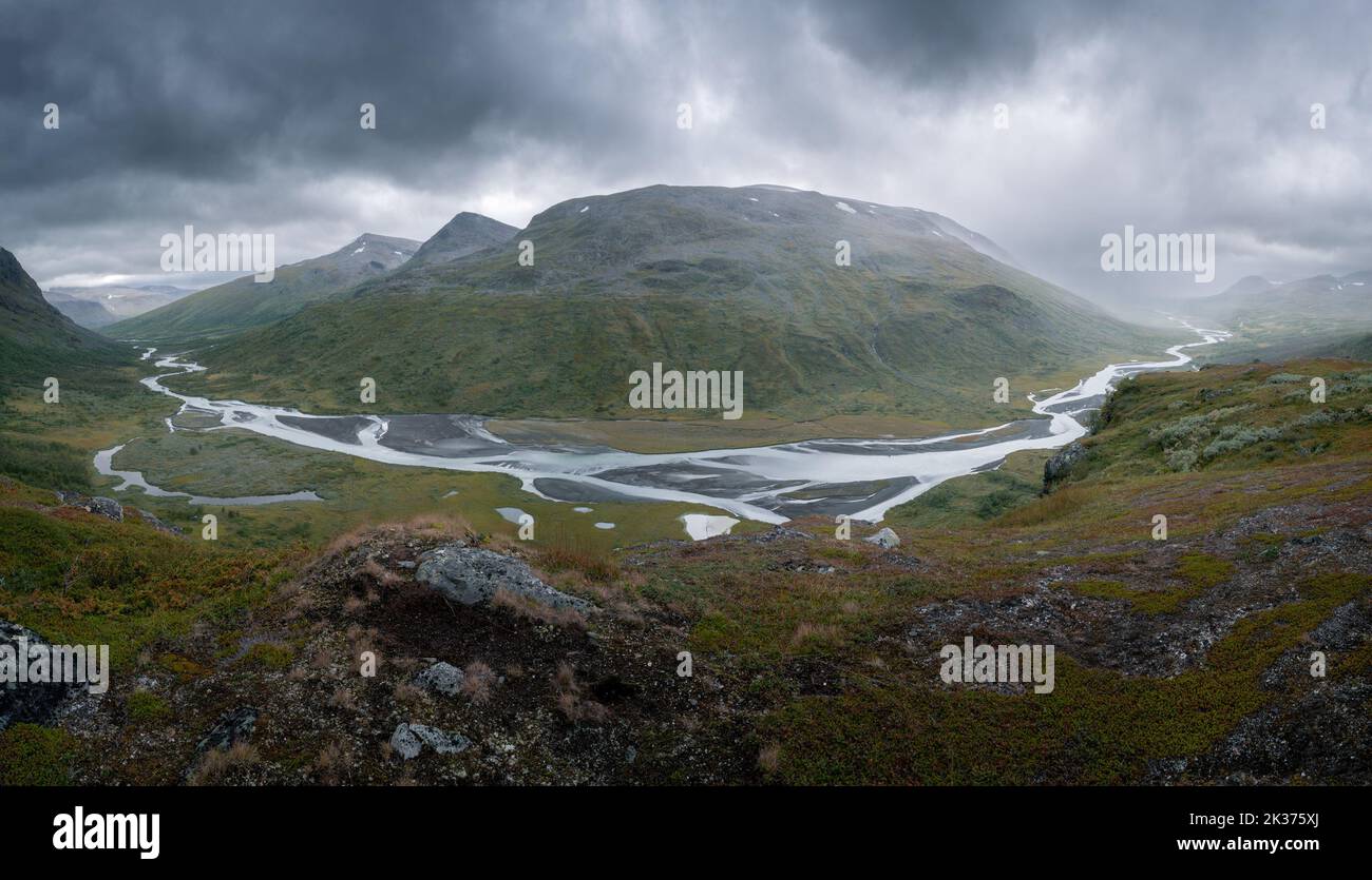 Wild river winds through remote rough arctic valley on a very cloudy and rainy day. Rahpajahka from Spokstenen viewpoint, Sarek National Park, Lapland Stock Photo