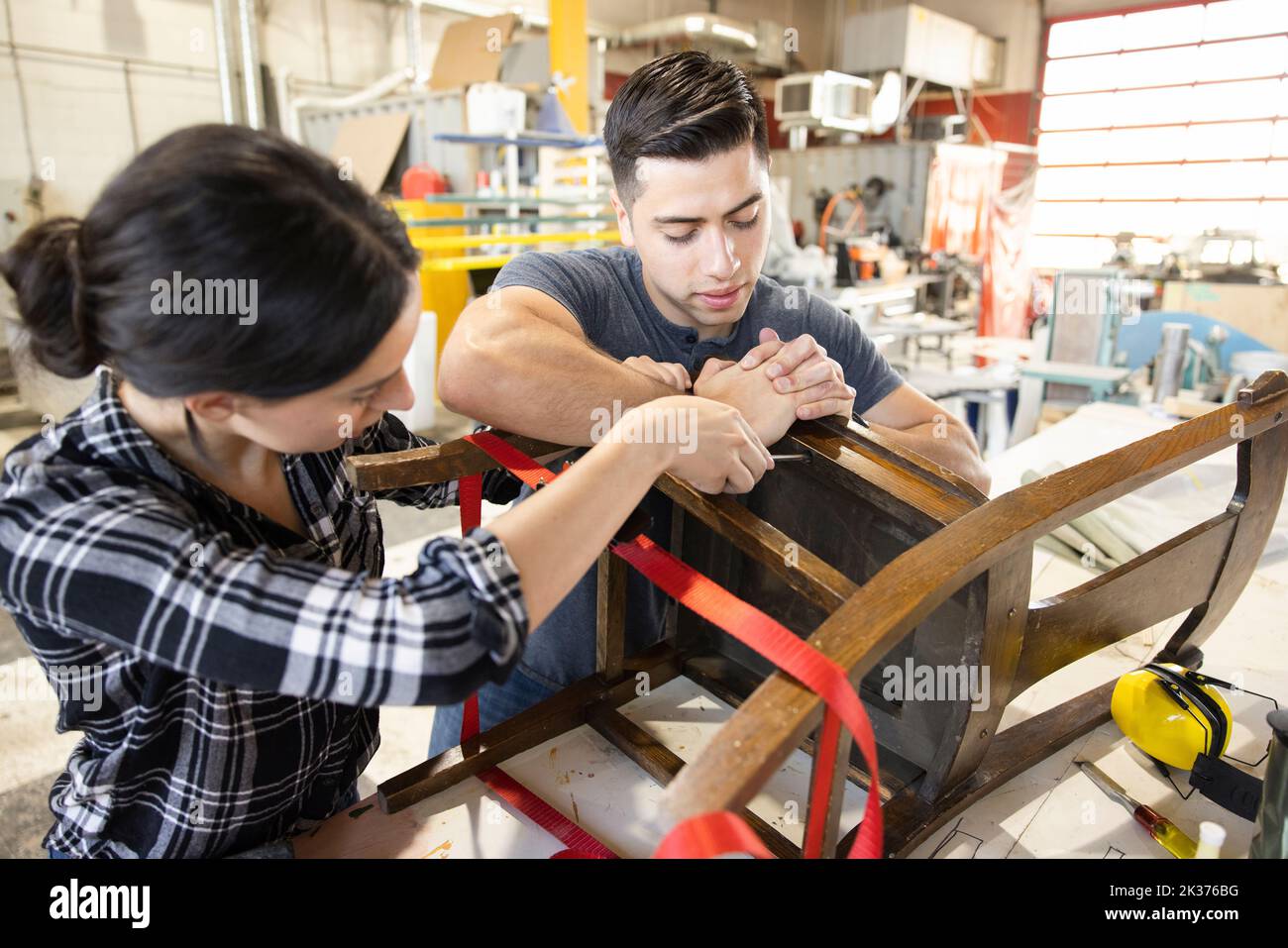 Woodworkers refinishing dining chair in wood shop Stock Photo