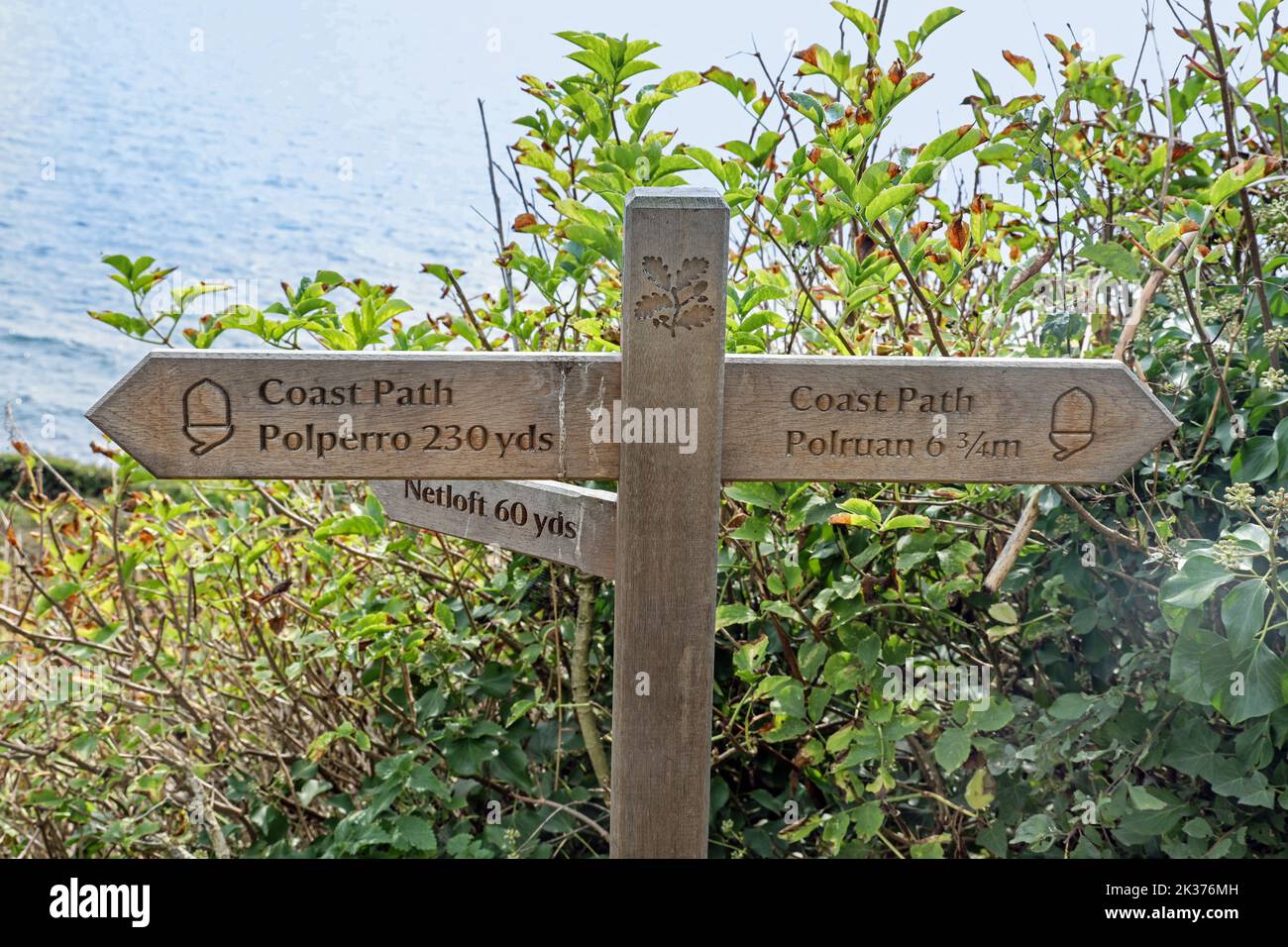 A beautifully crafted wooden signpost on the clifftop at Polperro in