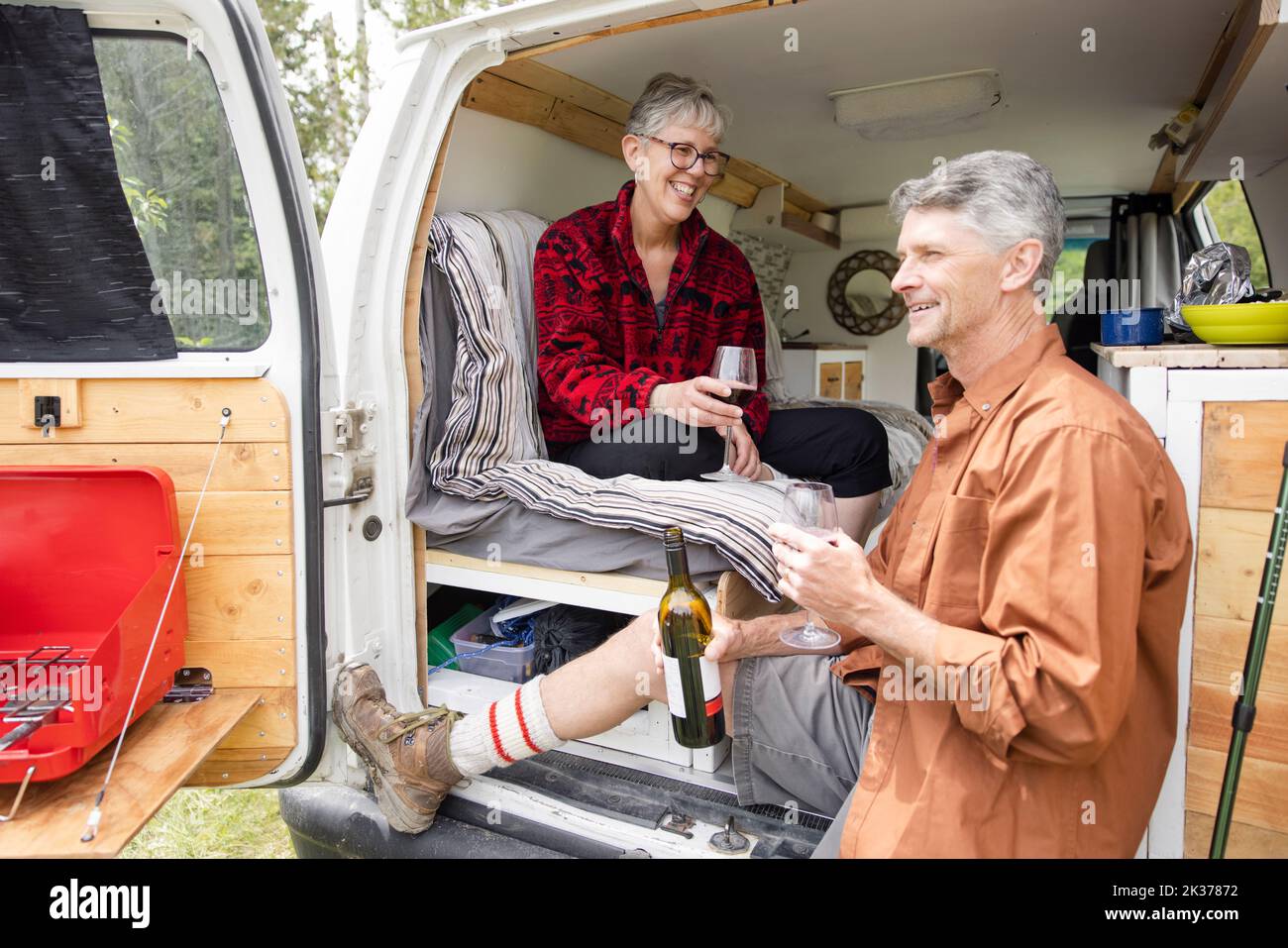Couple relaxing drinking wine in back of camper van Stock Photo Alamy