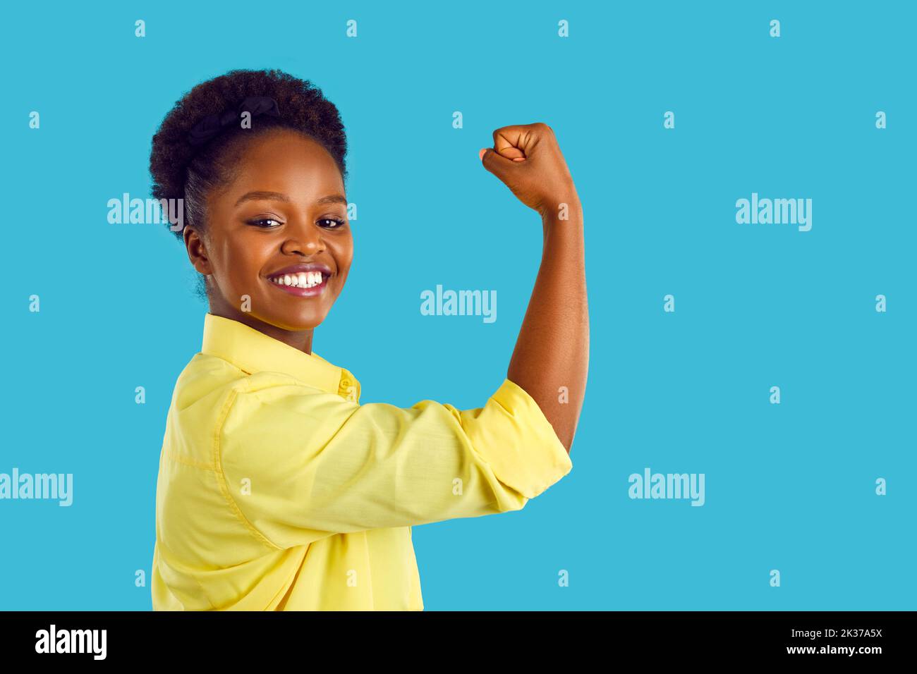 Portrait of happy strong young African American woman flexing her arm and smiling Stock Photo