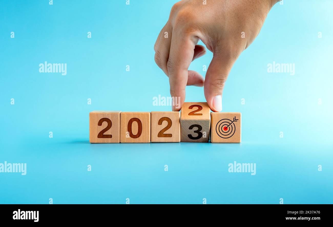 The calendar year 2022 changed to 2023 with the goal and successful concept. Hand turning wooden cube blocks for the transition from 2022 to 2023 with Stock Photo