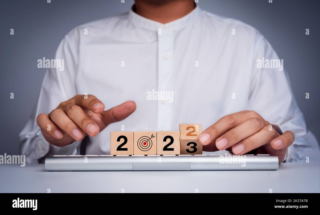 The calendar year 2022 changes to new year 2023, business goal and success plan concept. Wooden blocks turn by hand for the transition from 2022 to 20 Stock Photo