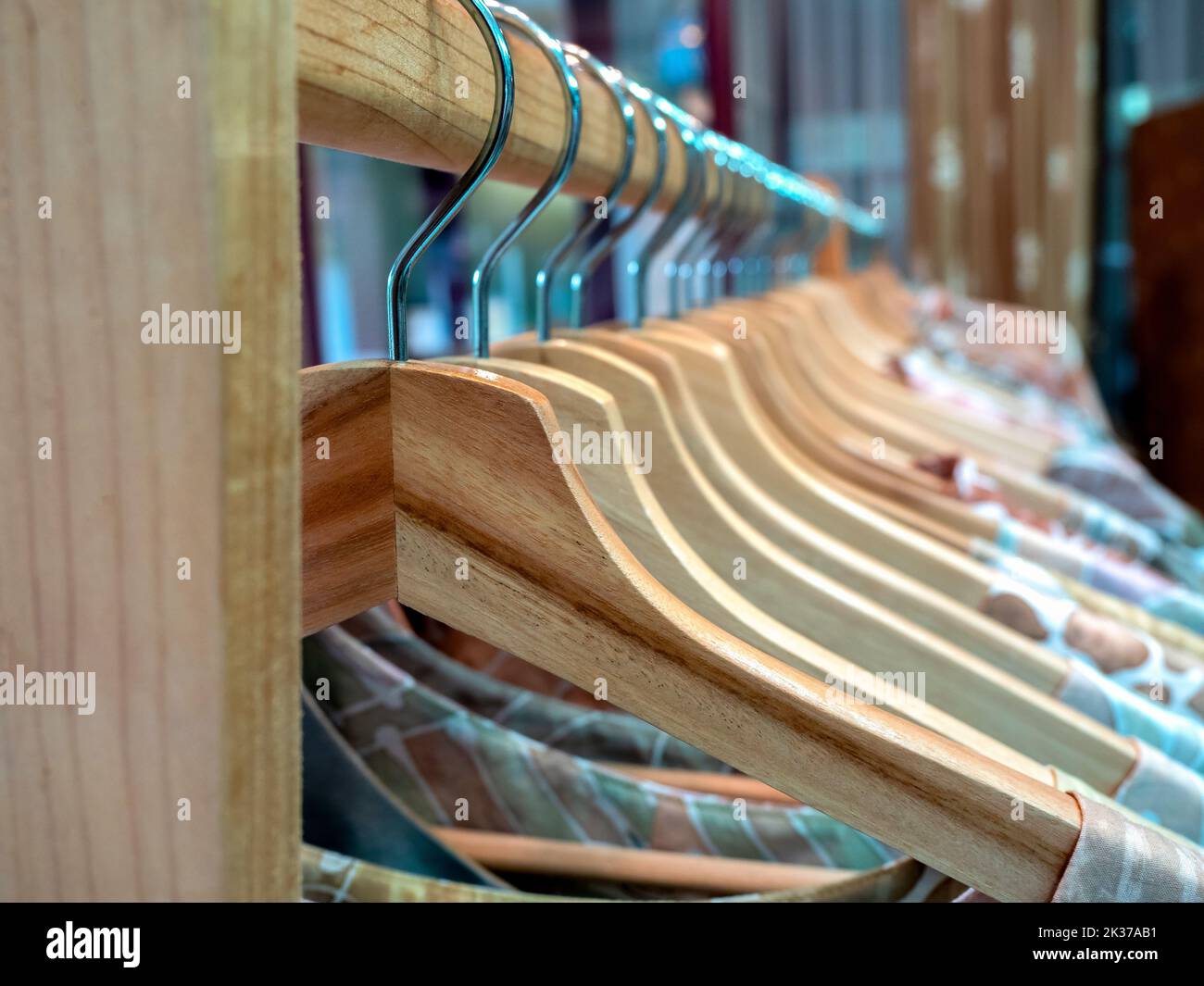 Close-up wooden clothes hangers with colorful shirts hanging on a wood cloth rack in Asian style fashion shop store. Stock Photo