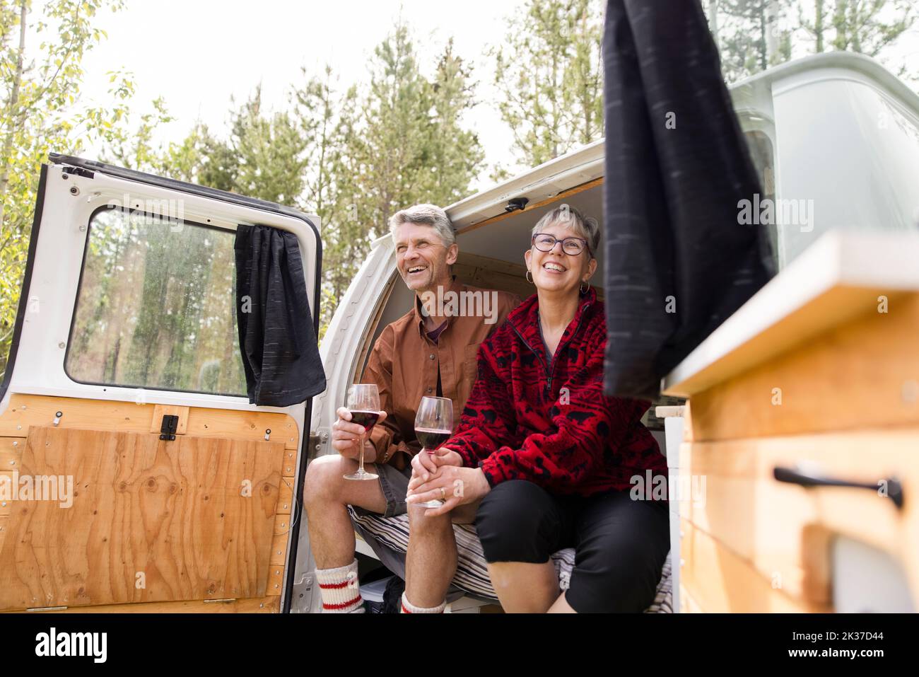 Couple drinking wine sitting in doorway of camper van Stock Photo Alamy