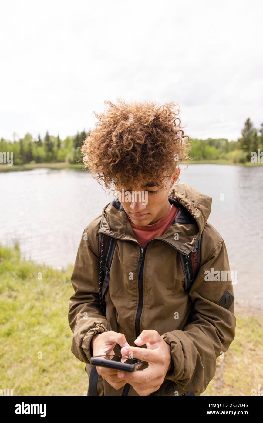 Portrait of boy using phone on riverbank Stock Photo