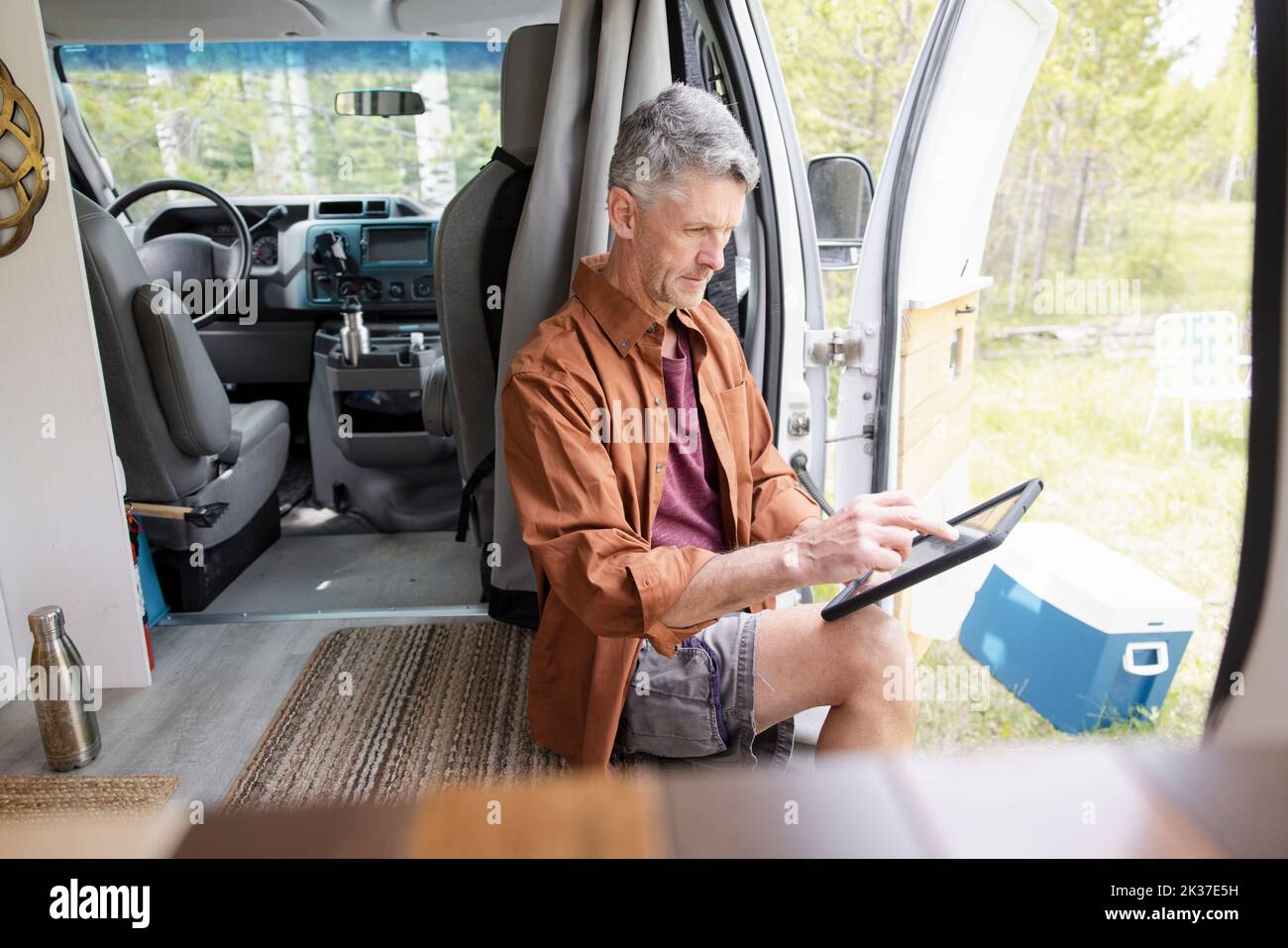 Man sitting in camper van reading tablet Stock Photo Alamy