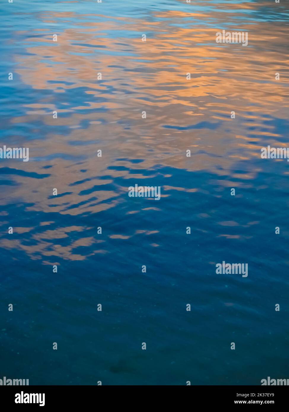 Sunrise sky reflected in calm water in blue and gold abstract Stock Photo