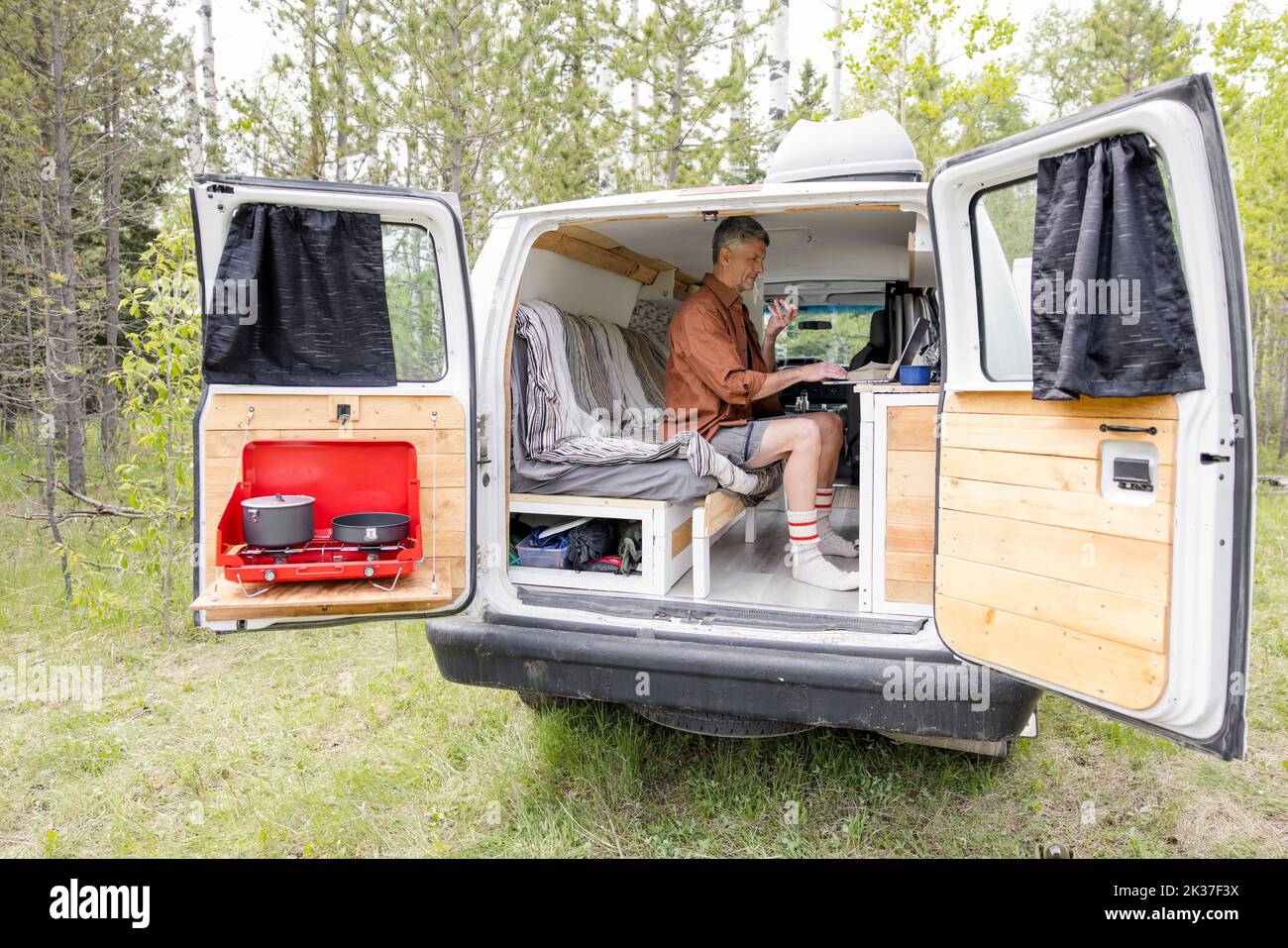 Man using laptop in camper van in forest Stock Photo Alamy