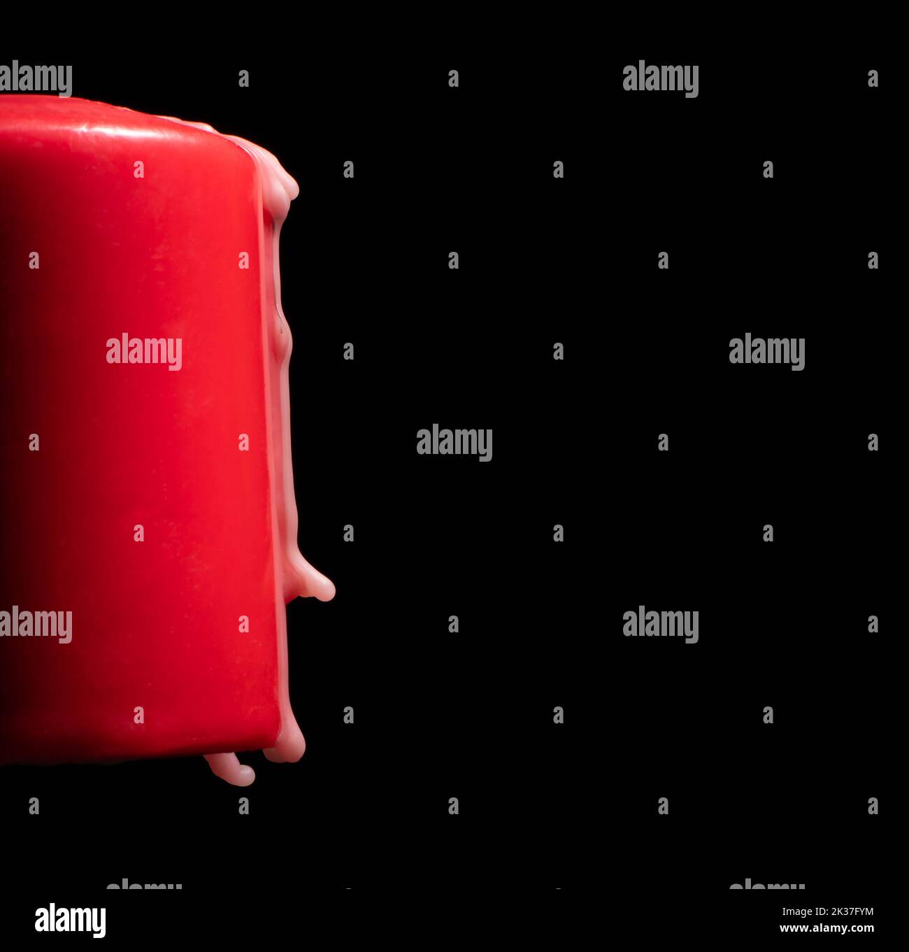 Red candle with wax dripping on a black background Stock Photo