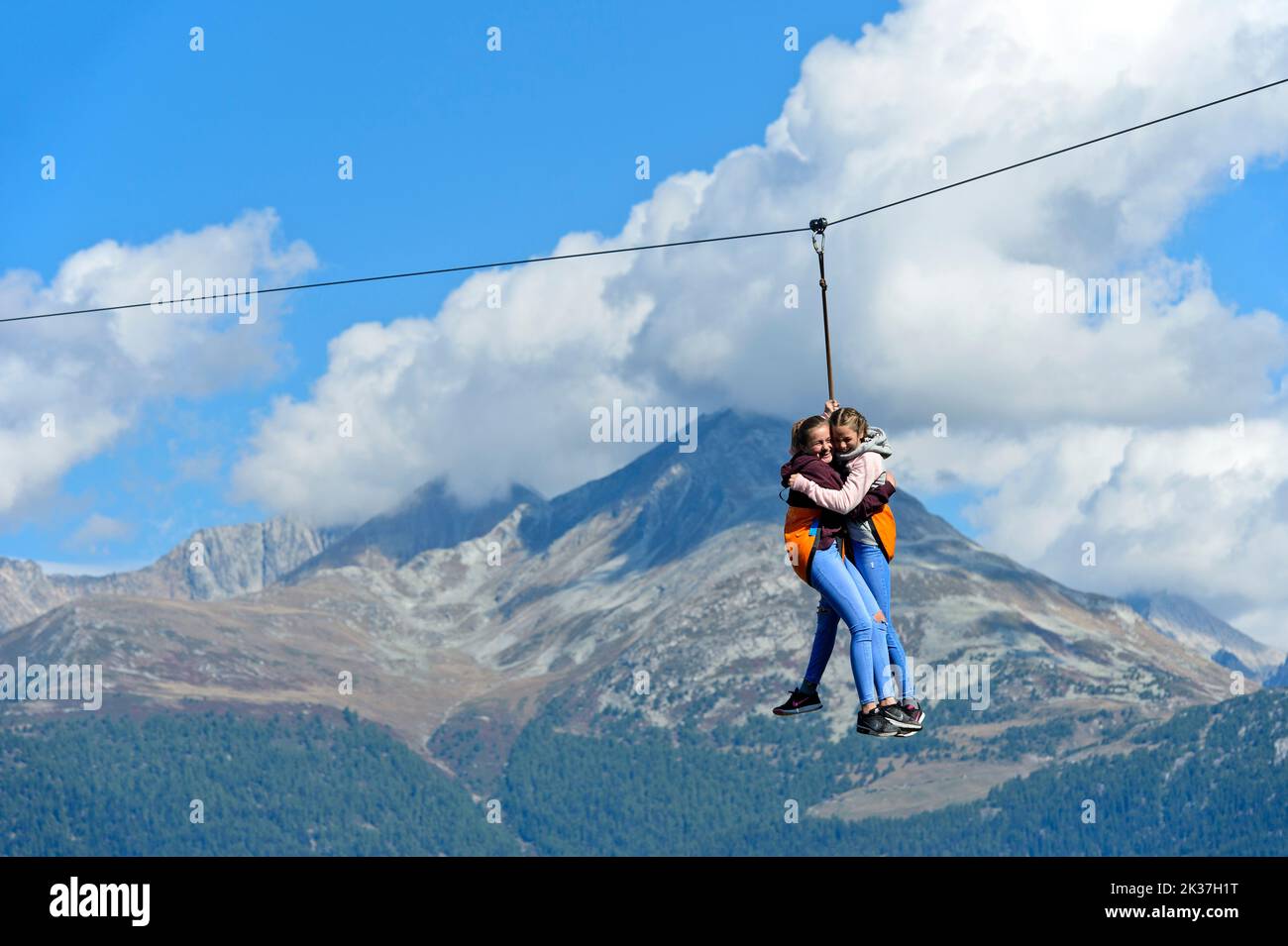 Two laughing girls hang on the rope of a zip line and slide down from the church tower to the ground, test of courage at the Chinderwältfäscht, childr Stock Photo