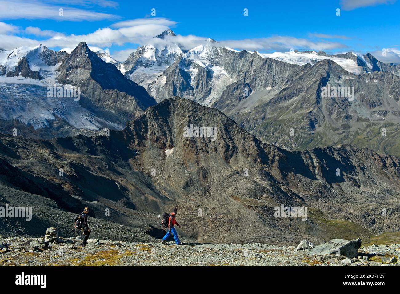 Mountain hikers hiking in the heart of the Valais Alps, peaks f.l.t.r. Blanc de Moming, Besso, Dent Blanche, Grand Cornier, Zinal, Val d'Anniviers, Va Stock Photo