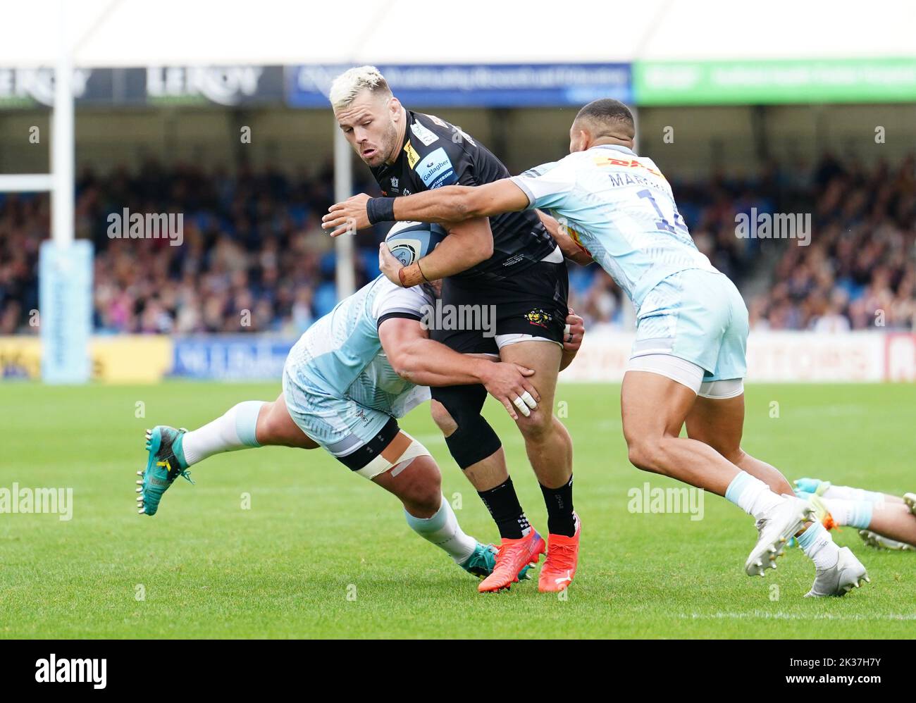 Exeter Chiefs' Luke Cowan-Dickie (centre) is tackled by Harlequins' Wilco Louw (left) and Joe Marchant during the Gallagher Premiership match at Sandy Park, Exeter. Picture date: Sunday September 25, 2022. Stock Photo