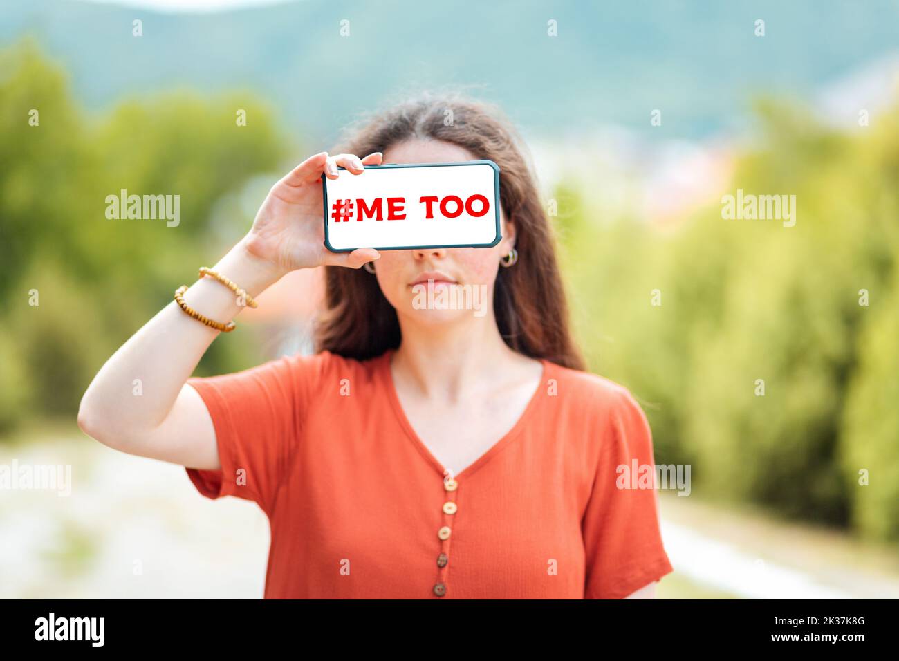 Portrait of a woman holding a smartphone while closing her eyes. Mock up. Outdoor. The concept of dependence on social networks and fake news. Stock Photo