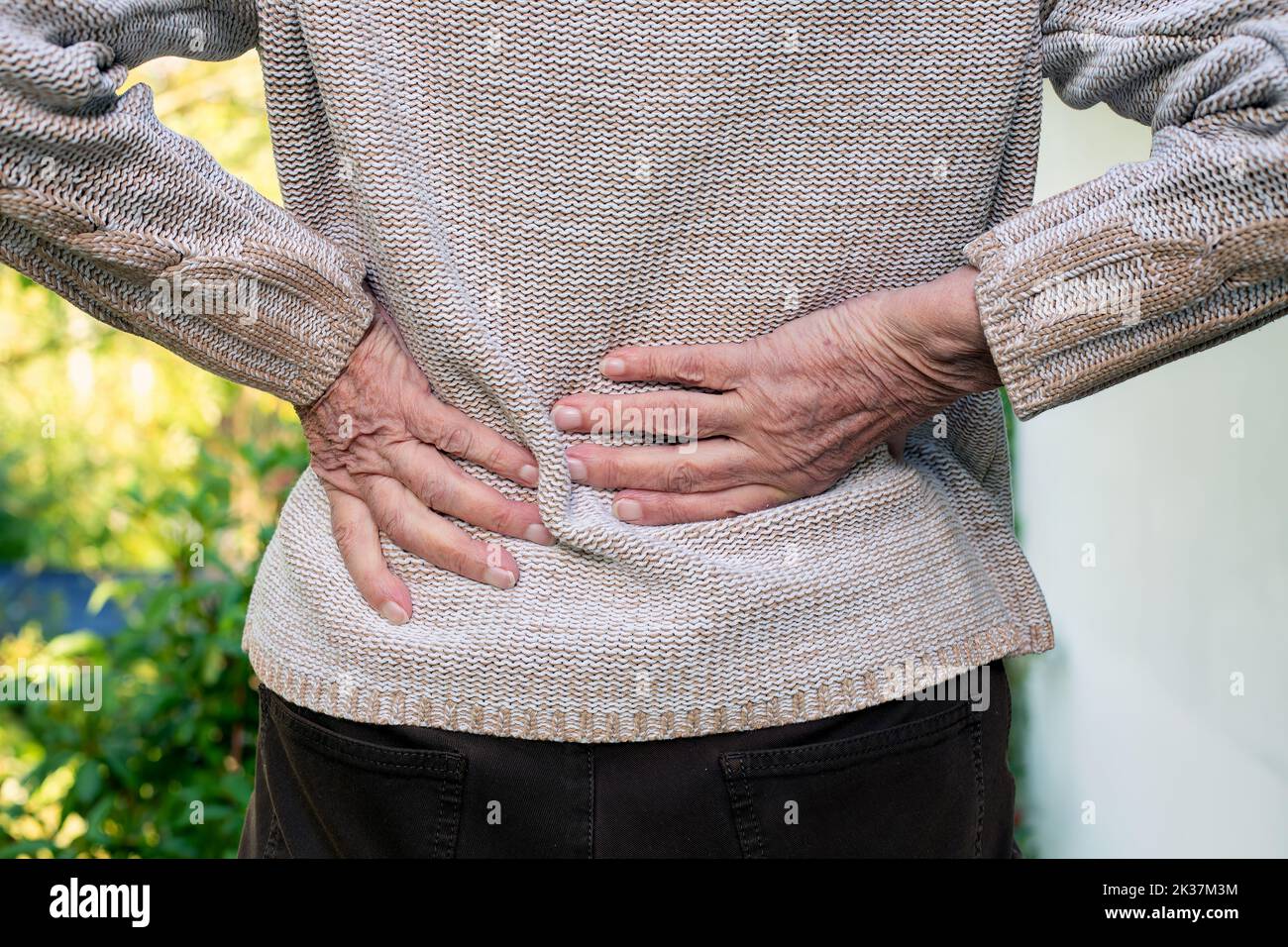 close-up of old woman rubbing her lower back Stock Photo