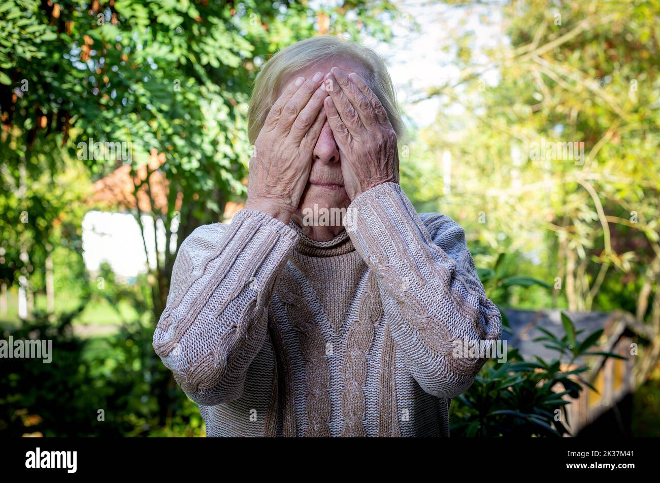 old woman covering her face with her hands Stock Photo