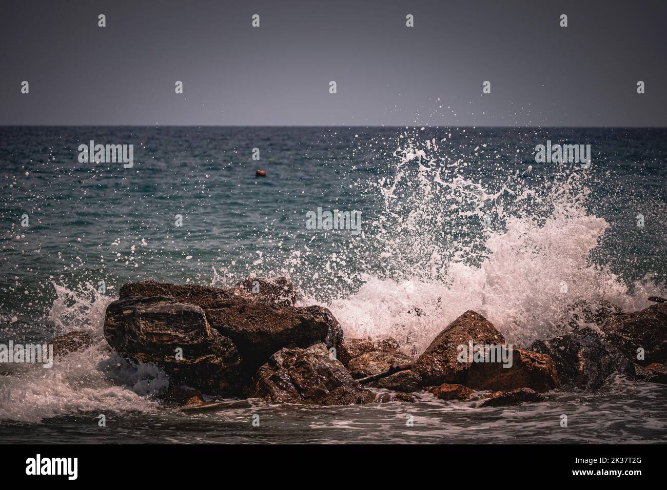 The foamy sea waves splashing onto rocks at the shoreline Stock Photo ...