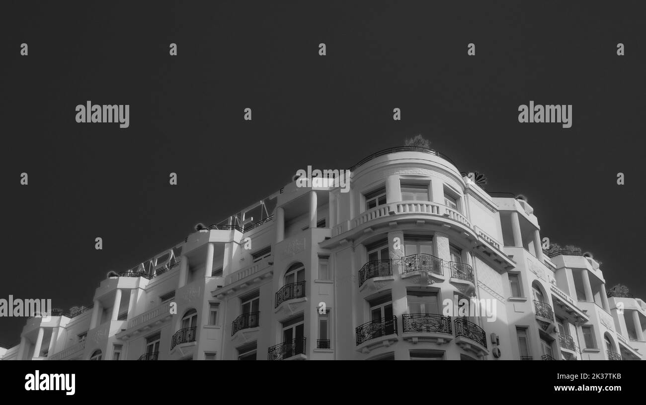 Greyscaled big white hotel building on the boulevard of Cannes in France. Black and White photo. Stock Photo