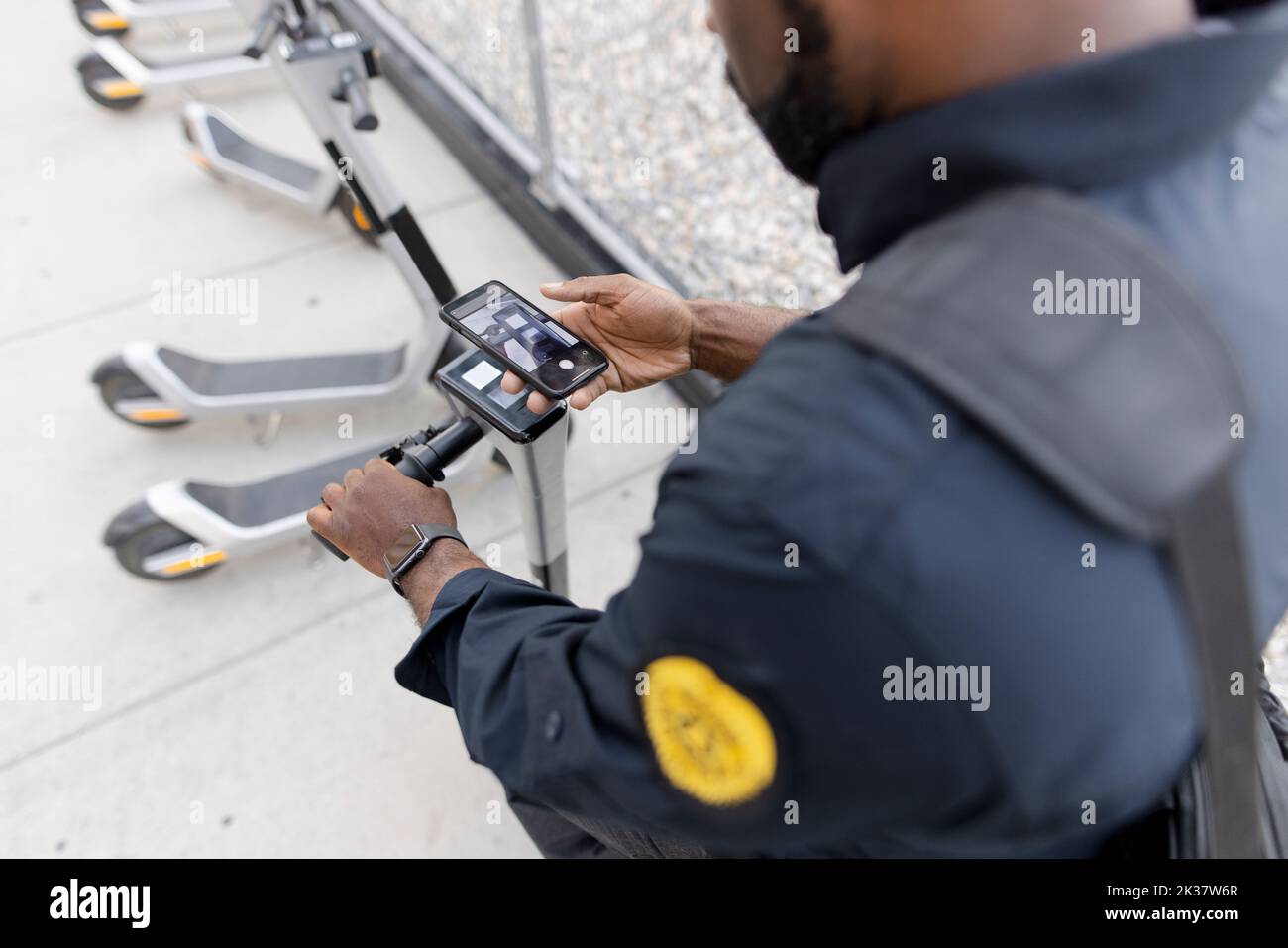 Security guard scanning barcode on phone to access scooter Stock Photo