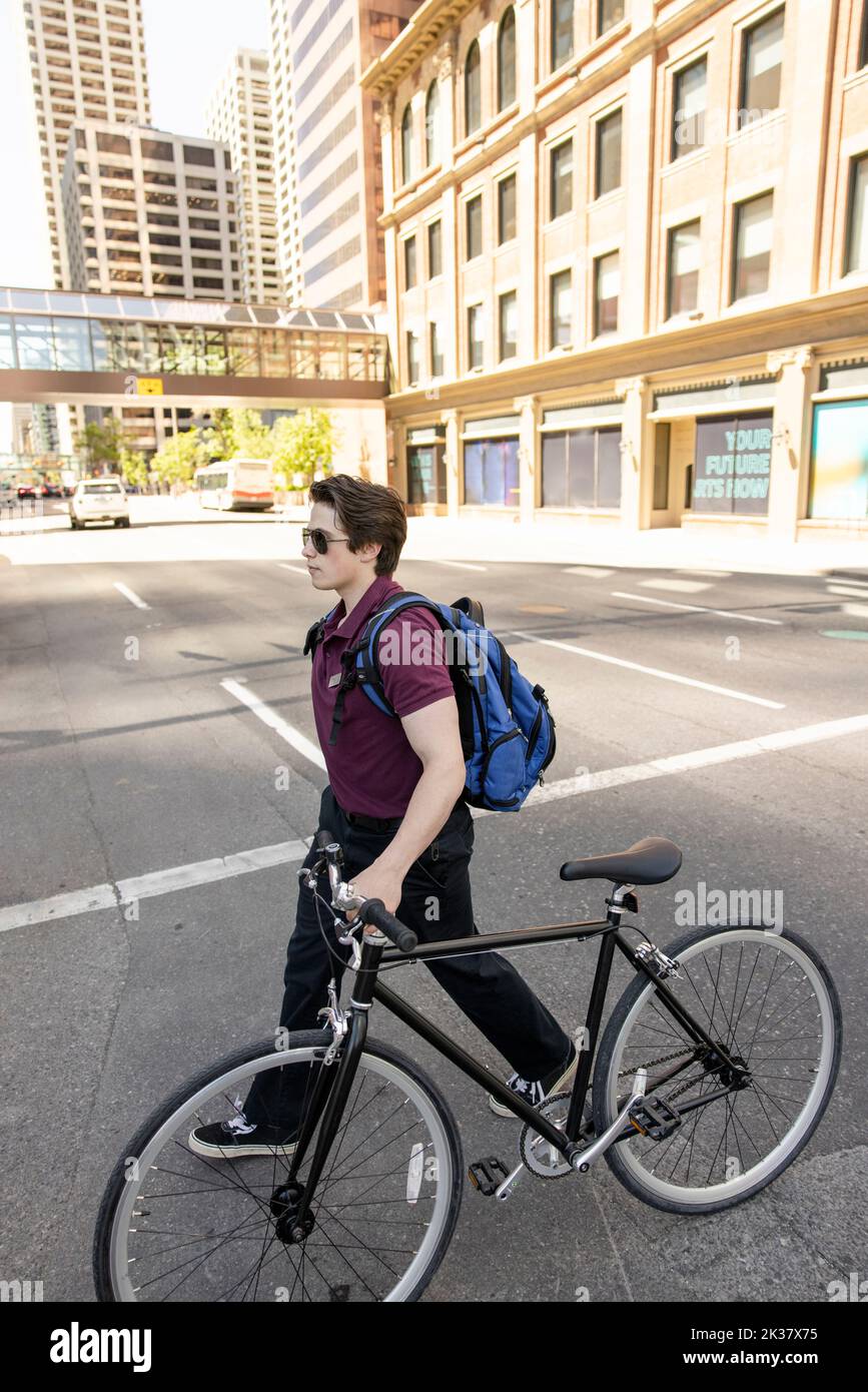 High angle view of teenage boy walking across road with bicycle Stock Photo