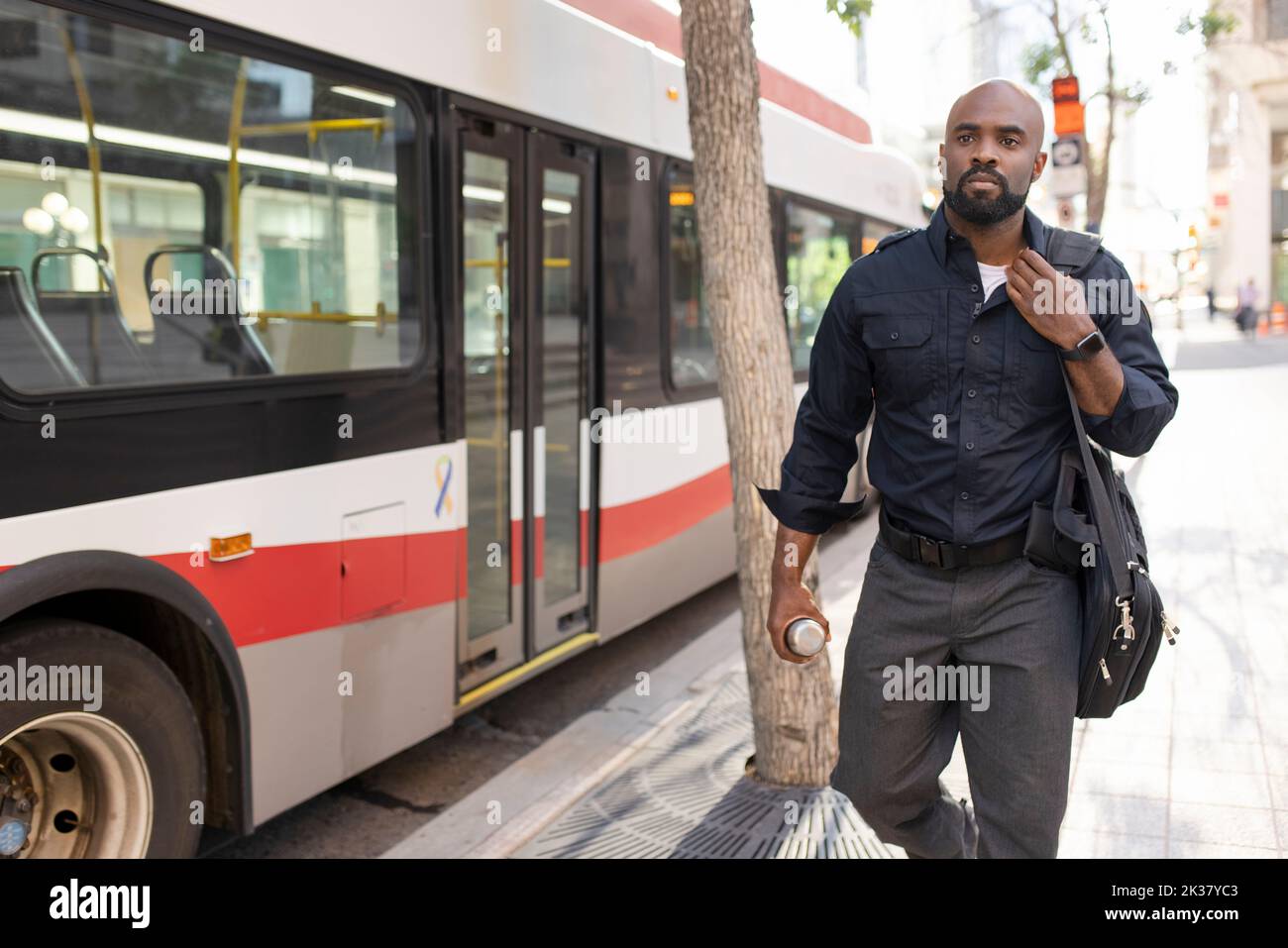 Security guard walking past bus in city center Stock Photo