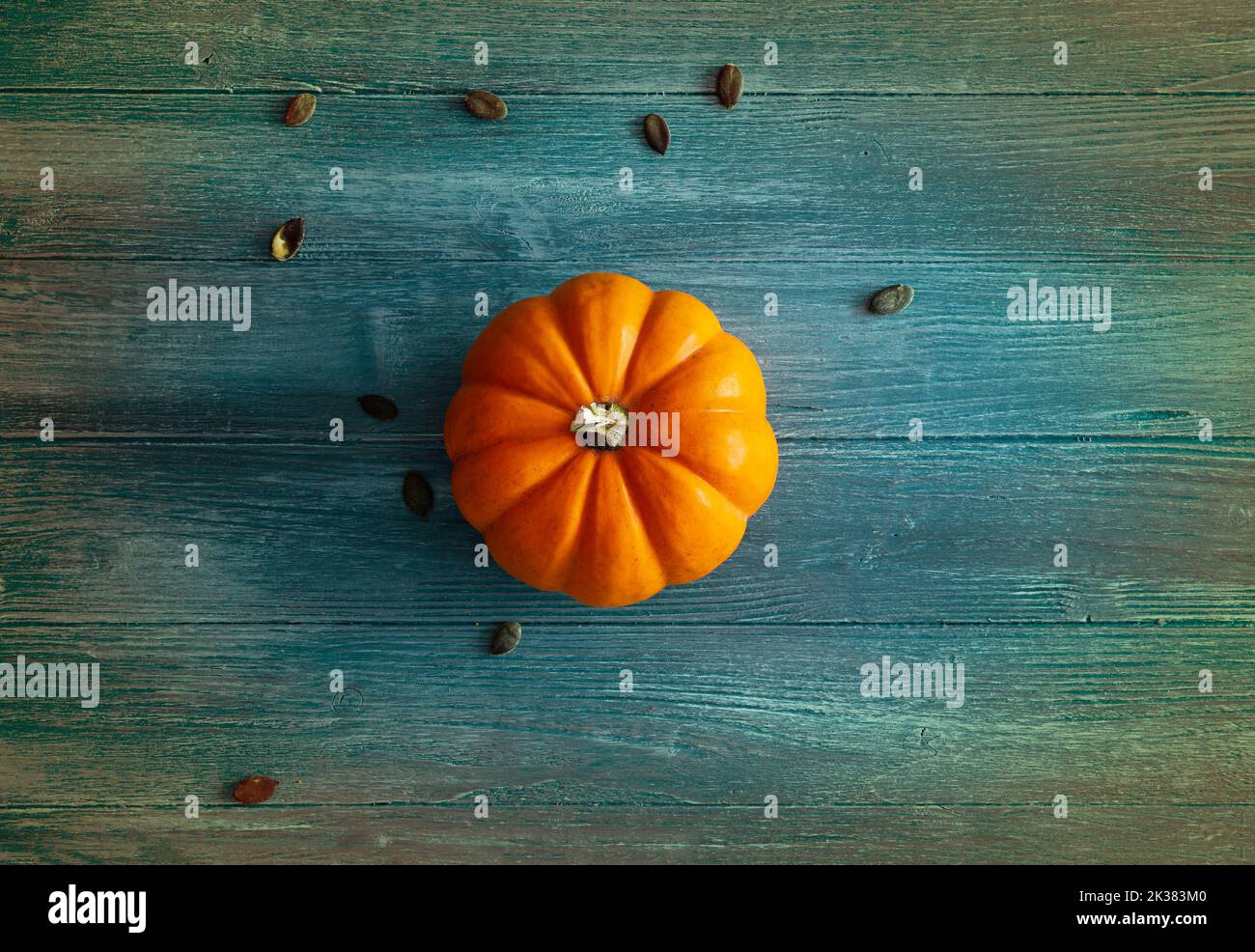 orange pumpkin on blue and colorful wooden background, ideal as a background for Halloween or autumn theme, orange pumpkin isolated Stock Photo