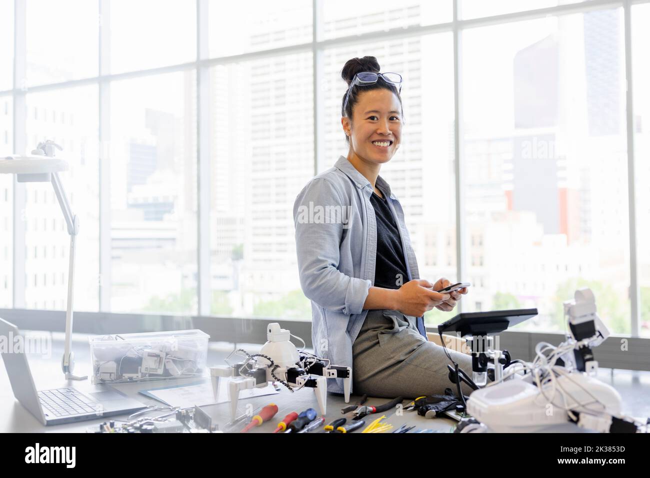 Portrait smiling female robotics engineer with smart phone Stock Photo