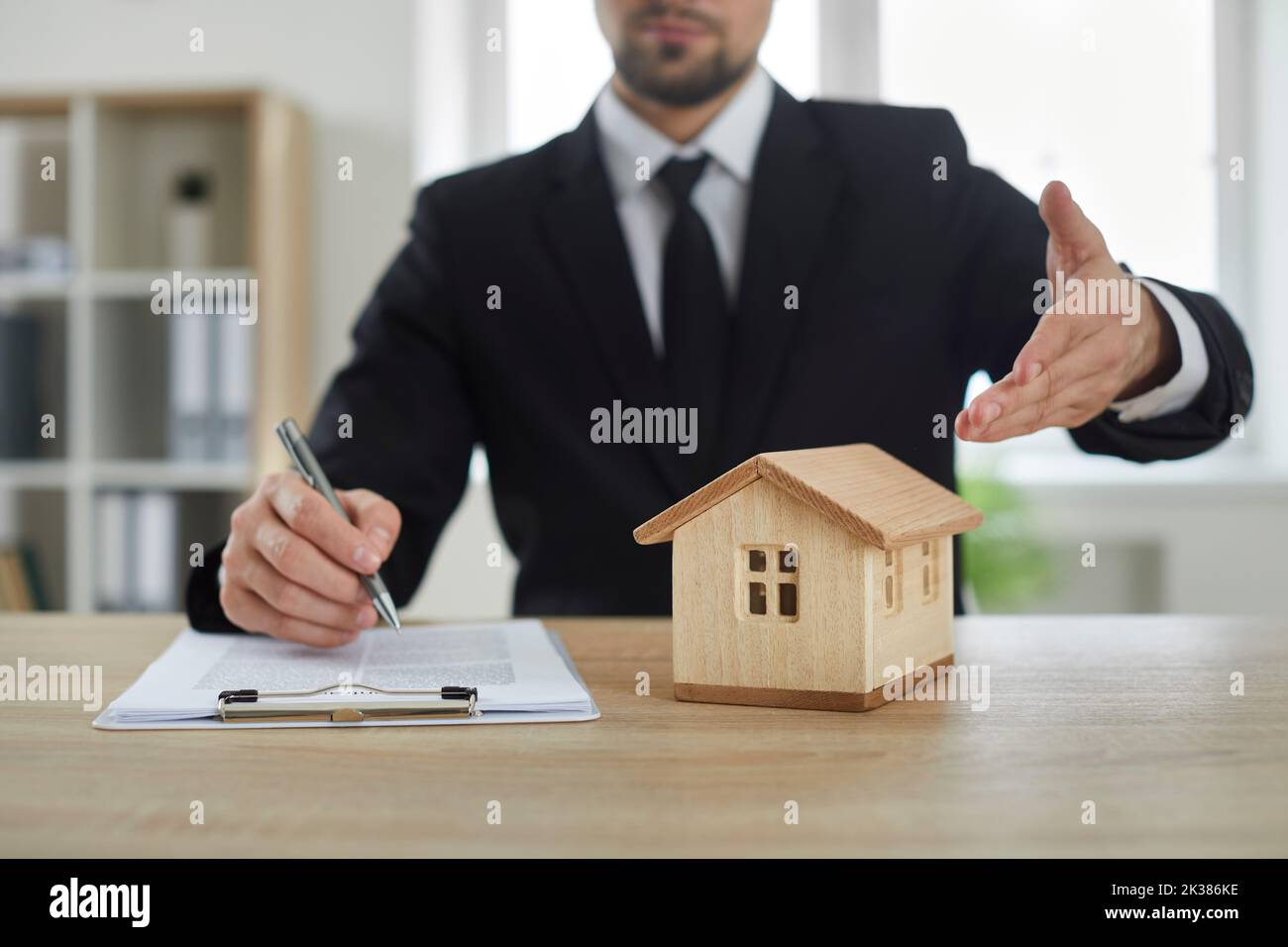 Realtor man pointing model of house located on table during signing contract for sale real estate Stock Photo
