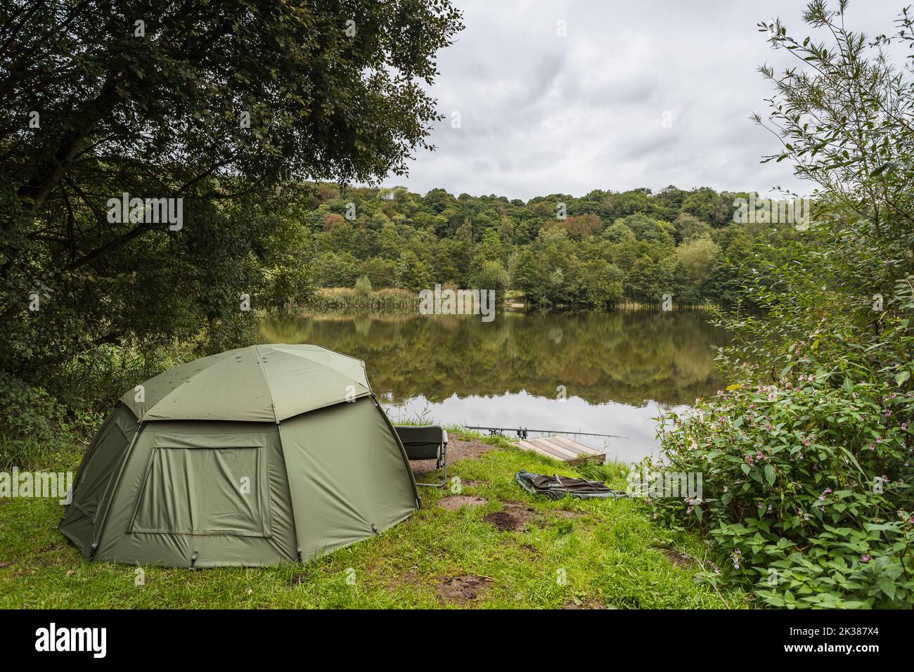 Image of an angler fishing from his bivy tent on the waters edge near Preston in September 2022. Stock Photo