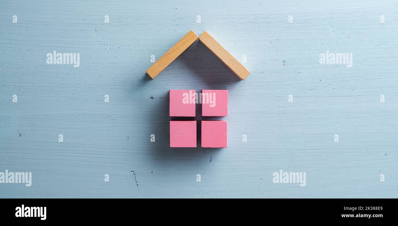 House made of pink wooden blocks placed over pastel blue background. Stock Photo