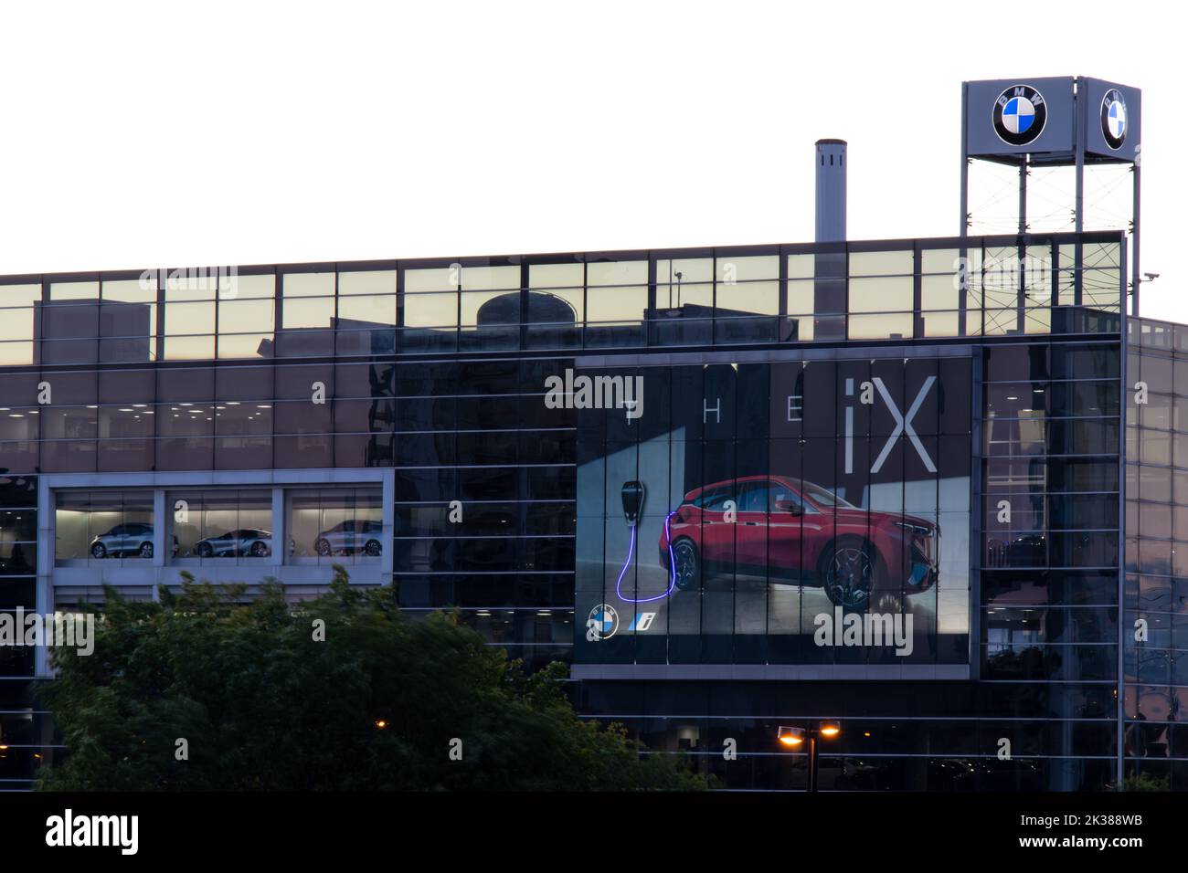 A large BMW dealership, with a billboard for their new electric iX car, is seen illuminated at dawn in Toronto. Stock Photo