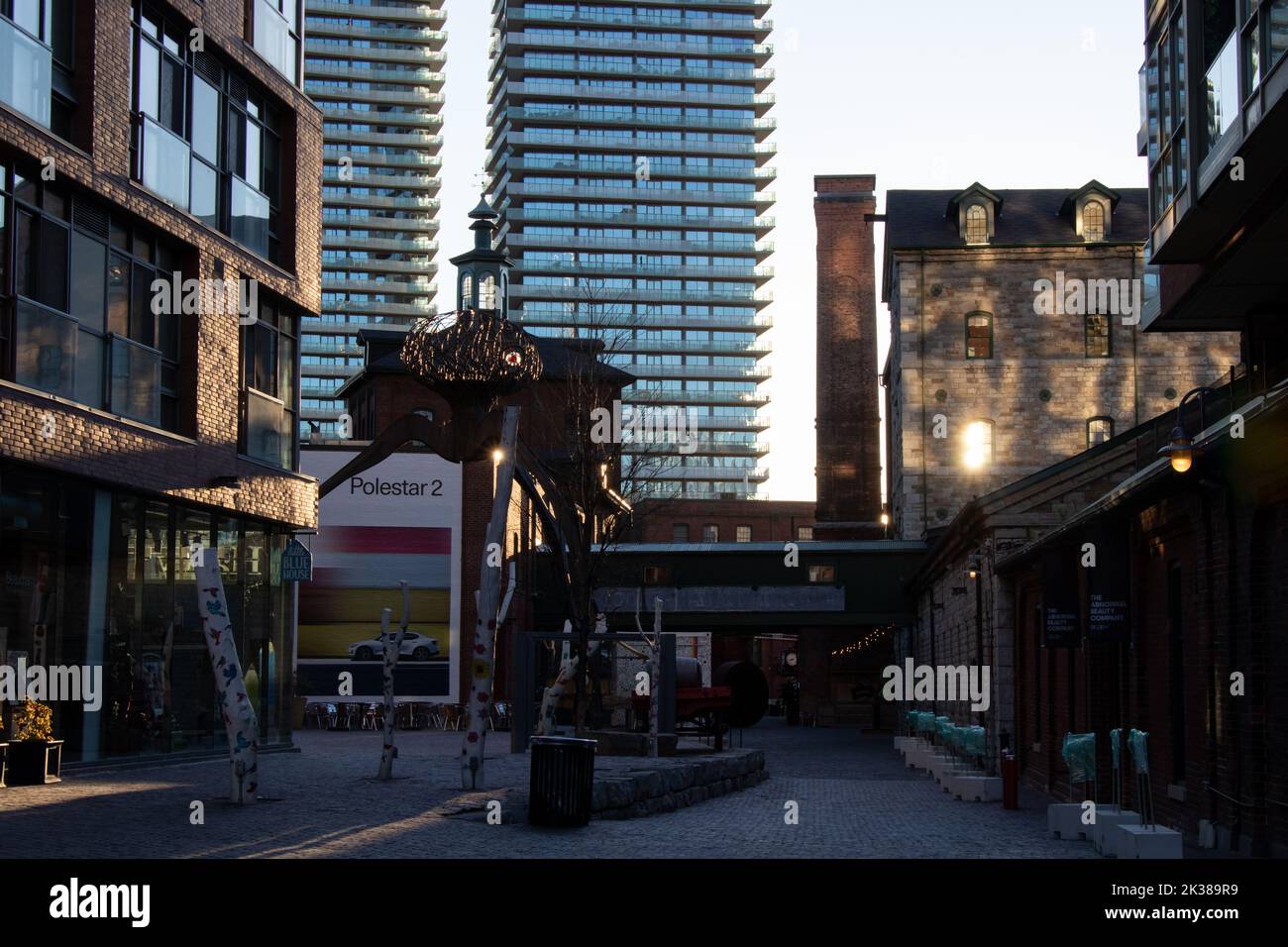 The Toronto Distillery District is seen in the early morning as the sun shines; an advertisement for the Polestar 2 electric vehicle on a building. Stock Photo