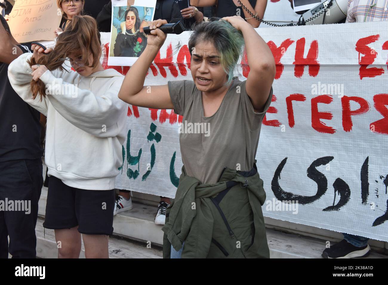 Athens, Greece. 24th September 2022. Two women cut their hair during a protest over the death of 22-year-old Iranian woman Mahsa Amini after being detained by morality police in Tehran for violating hijab rules. Credit: Nicolas Koutsokostas/Alamy Stock Photo. Stock Photo