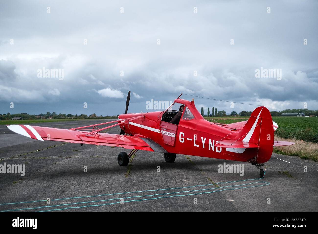 A red glider tug on the runway at Rufforth Airfield, York with a tow rope trailing behind ready to tow a glider into the air. Stock Photo