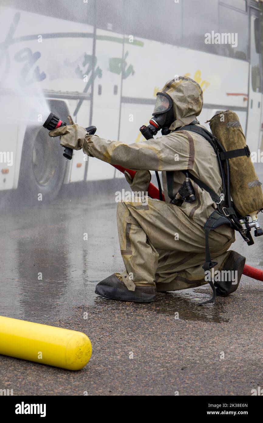 A firefighter in a suit with an oxygen mask extinguishes the fire Stock