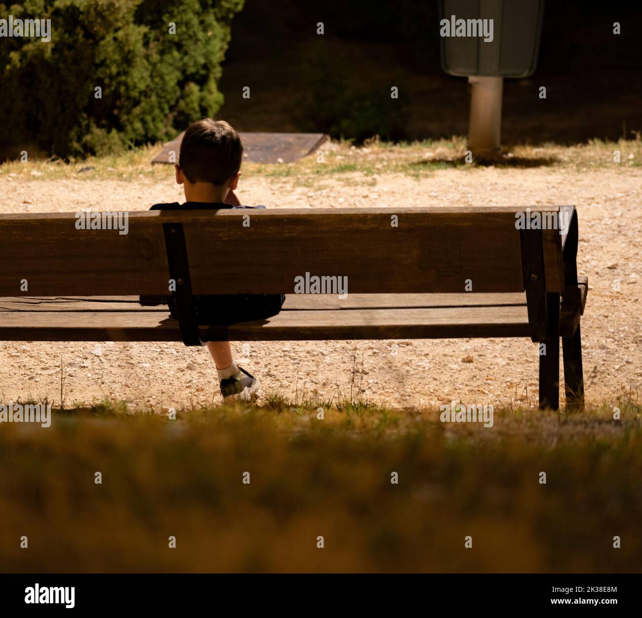 Kid sad alone in the dark at night under a streetlight sitting in a