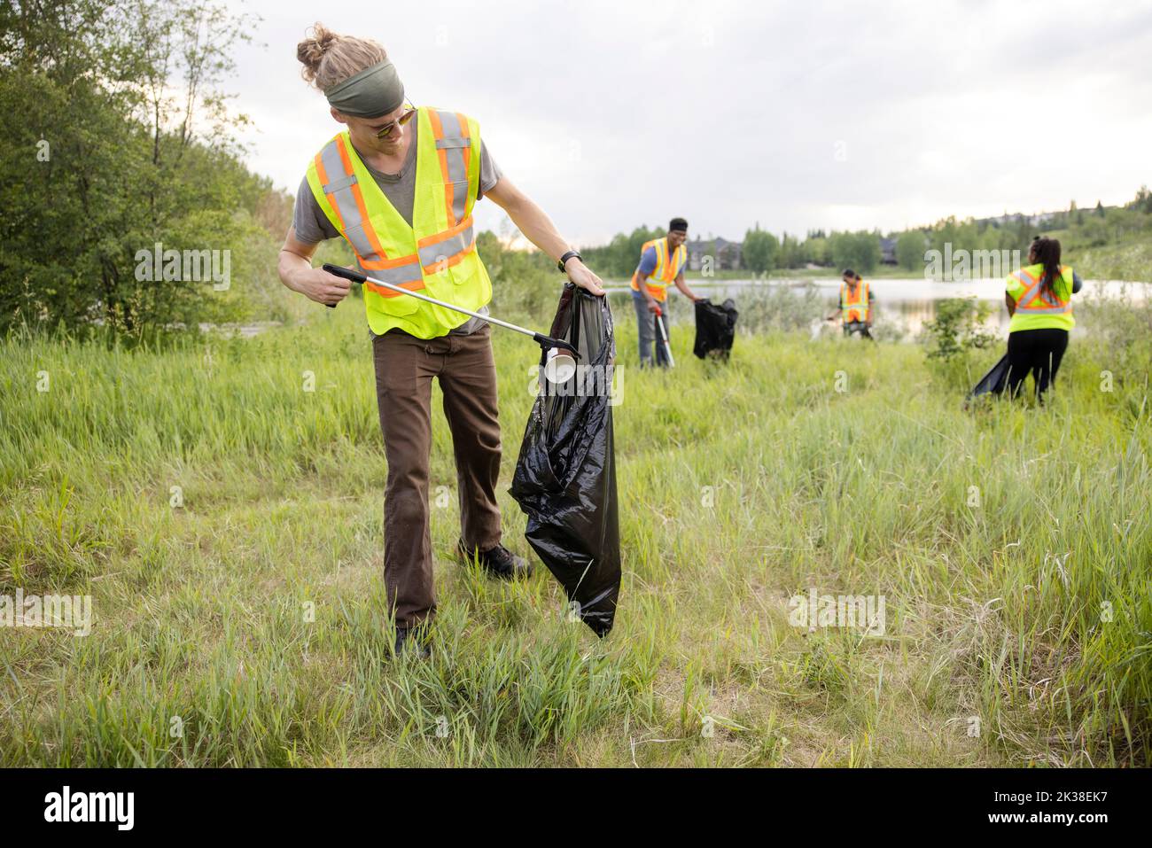 Conservation volunteers litter picking next to lake Stock Photo Alamy