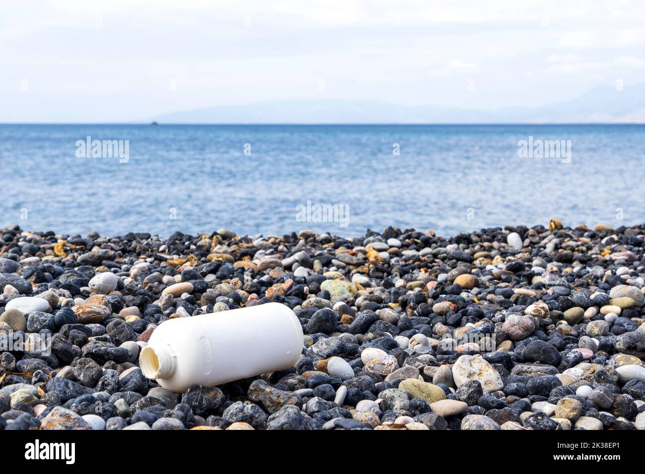 An empty plastic bottle on a pebble beach, the concept of plastic