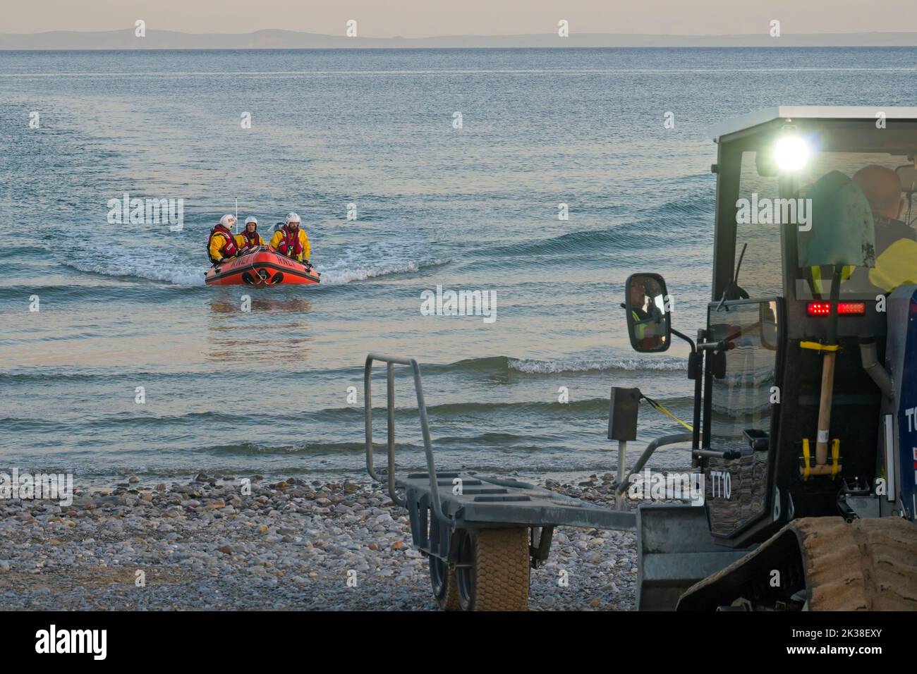 Horton Gower Wales UK RNLI Inshore Lifeboat returning to Lifeboat Station after exercise Beach recovery vehicle and crew assisting in shallow waters. Stock Photo