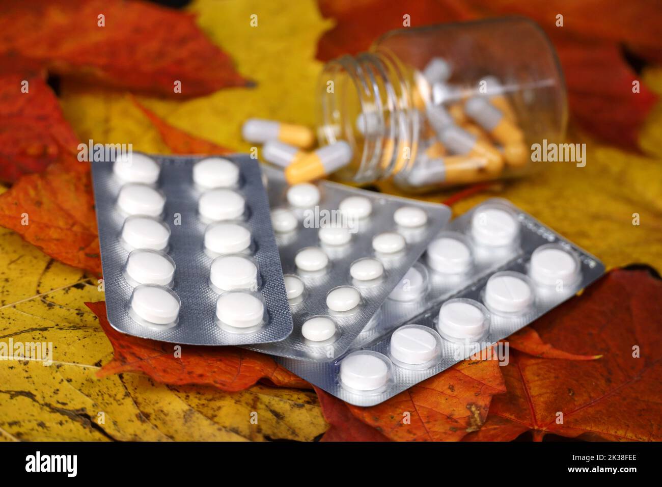 Pills on autumn maple leaves, bottle with scattered capsules. Pharmacy, antidepressants, vitamins for immunity in flu season Stock Photo