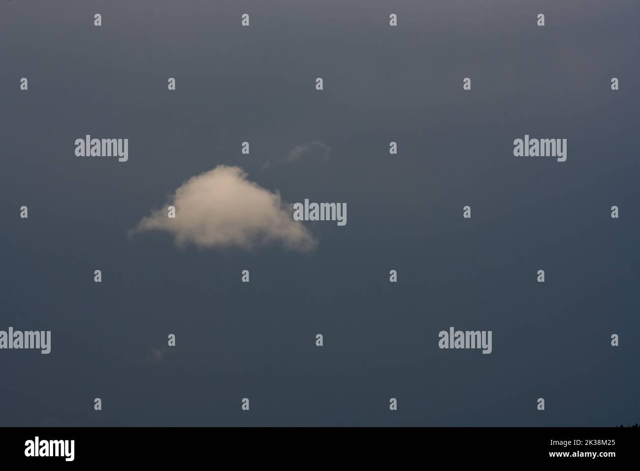 Single Puffy Cloud In Gray Sky with copy space to right Stock Photo