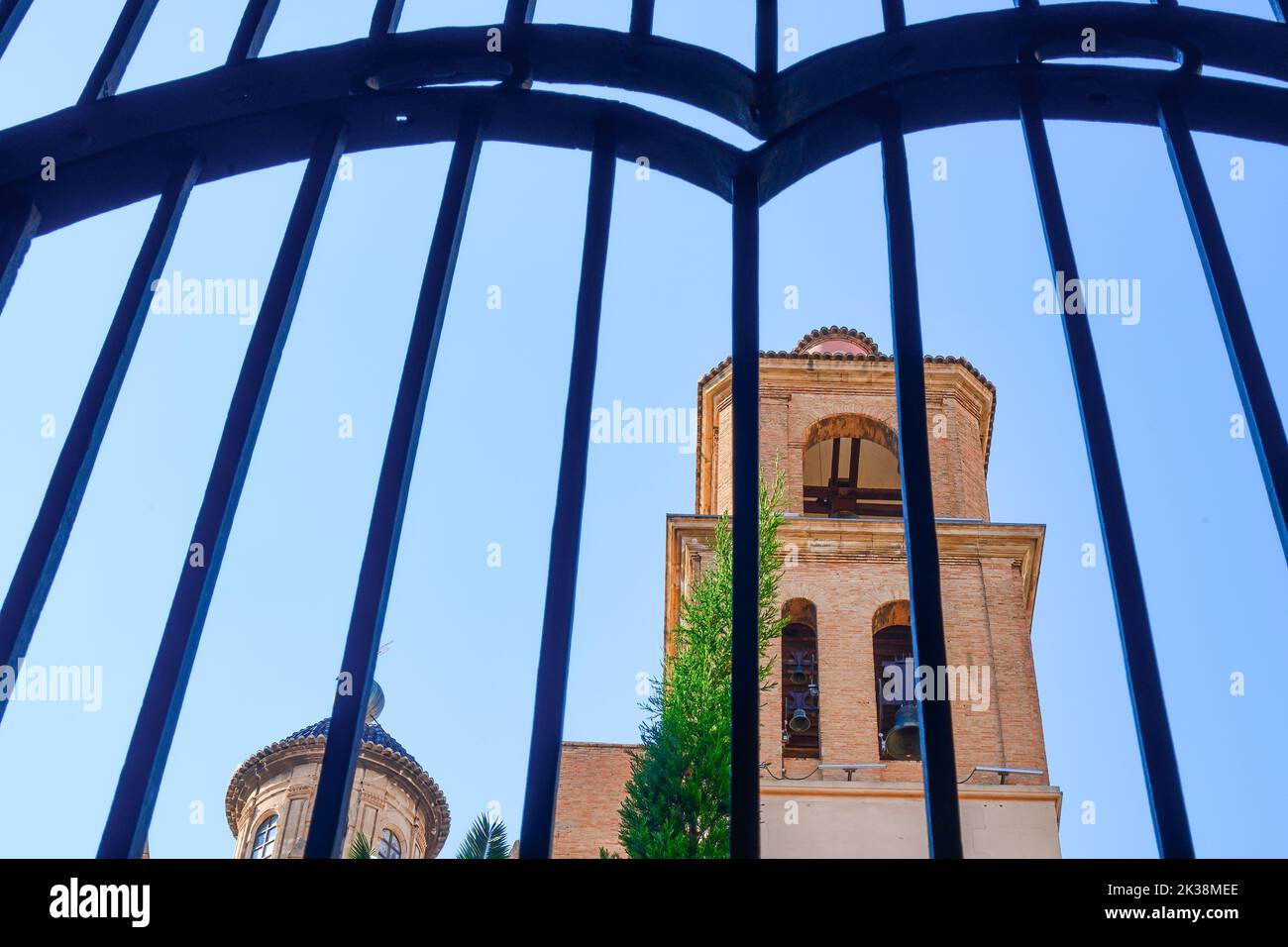 Bell tower seen from inside of the Catholic medieval church. The structure is framed in metallic fence. Stock Photo