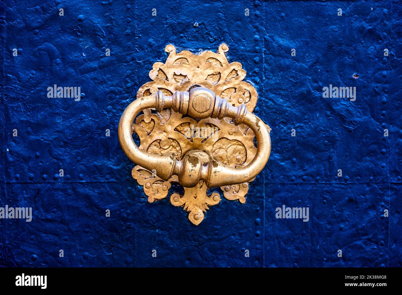 Close-up of a golden medieval door knocker in the entrance door. Stock Photo