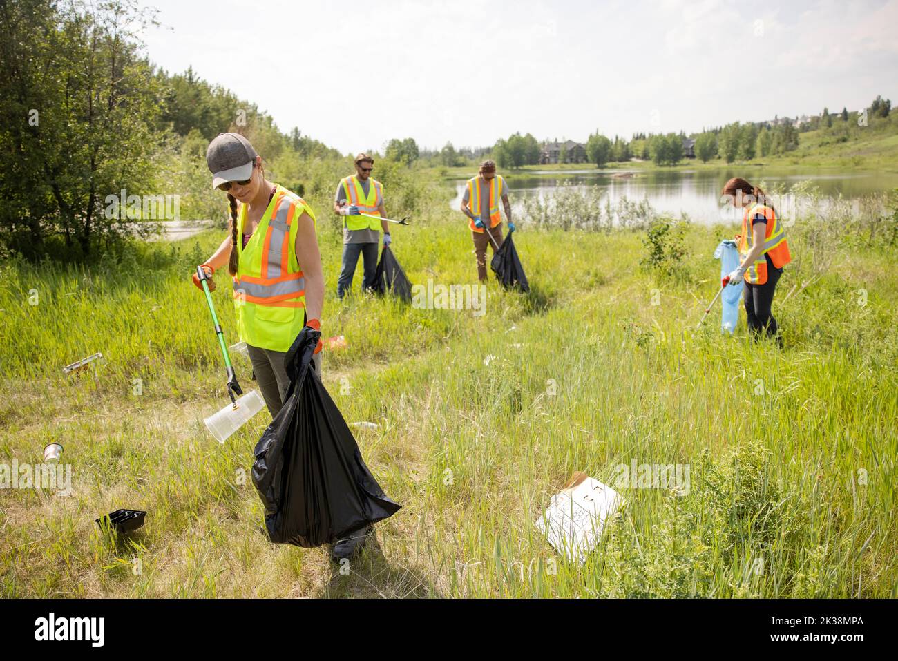 Woman litter picking next to lake Stock Photo Alamy