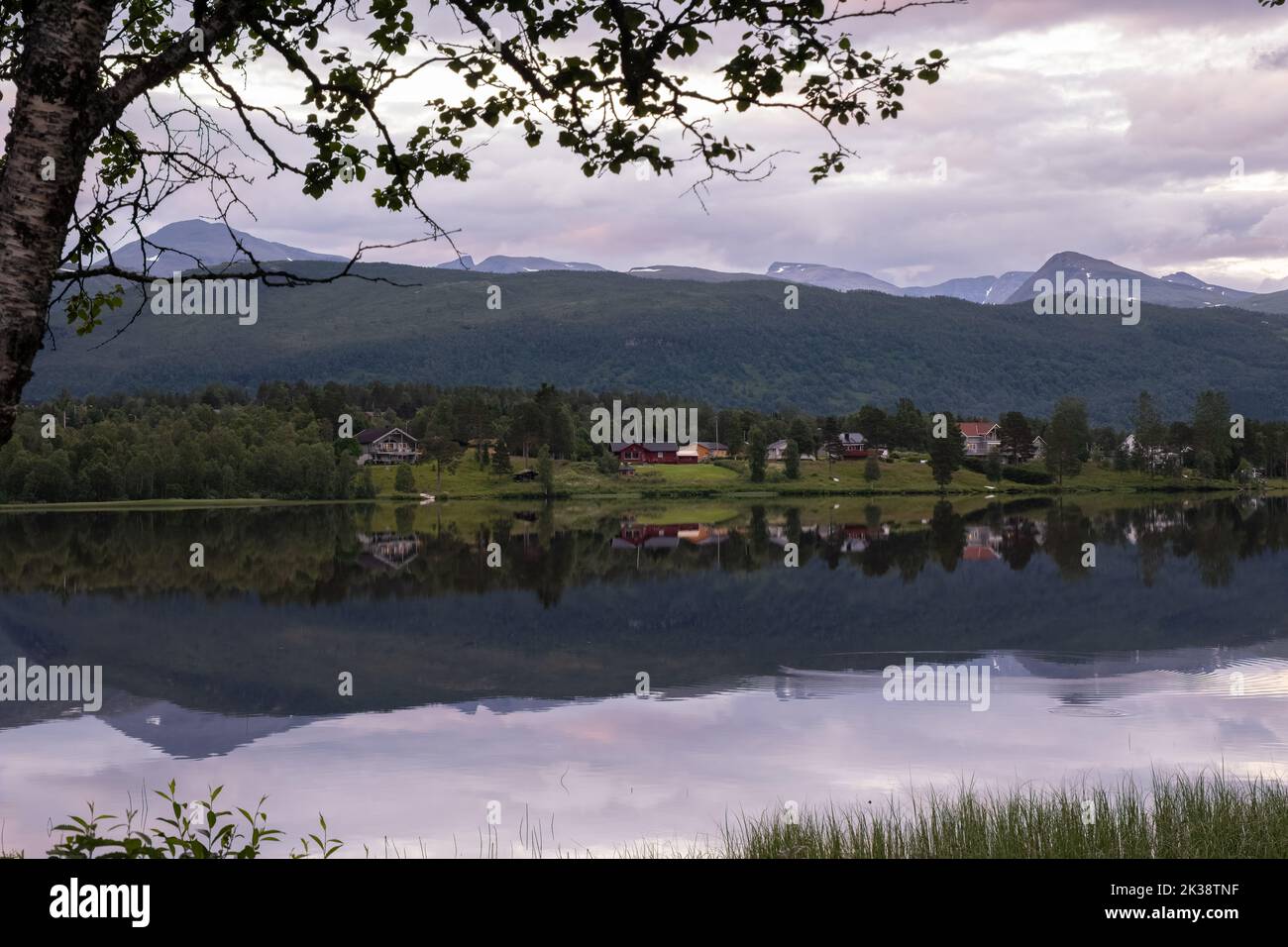 Wonderful landscapes in Norway. Nordland. Beautiful scenery of a valley with houses on the hill. Mirror in the lake. Calm water in a cloudy summer day Stock Photo
