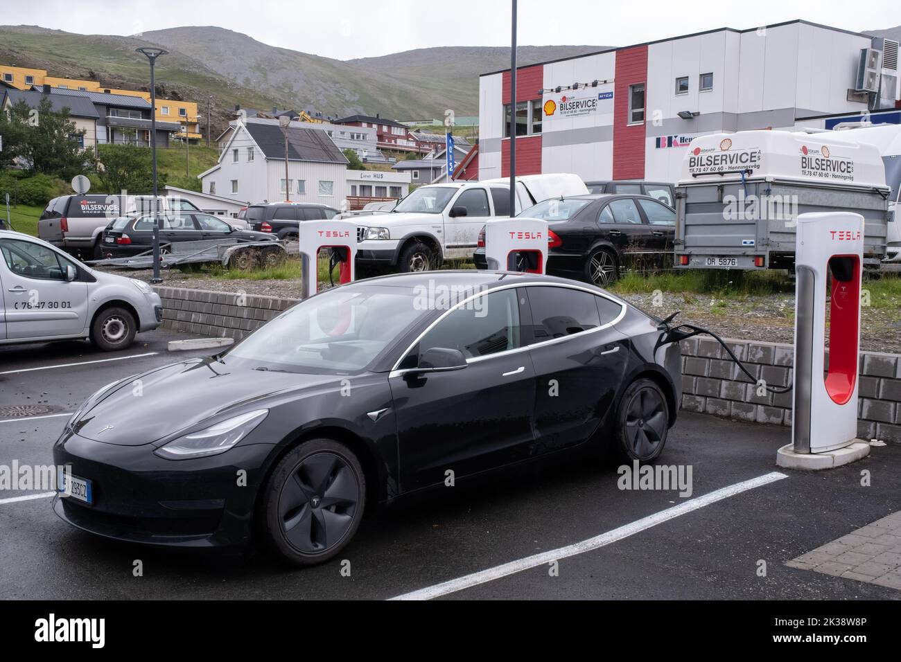 Honningsvag, Norway - July 26, 2022: A static shot of a solid black Tesla Model 3 dual motor charging at the Honningsvag Supercharger in a cloudy summ Stock Photo